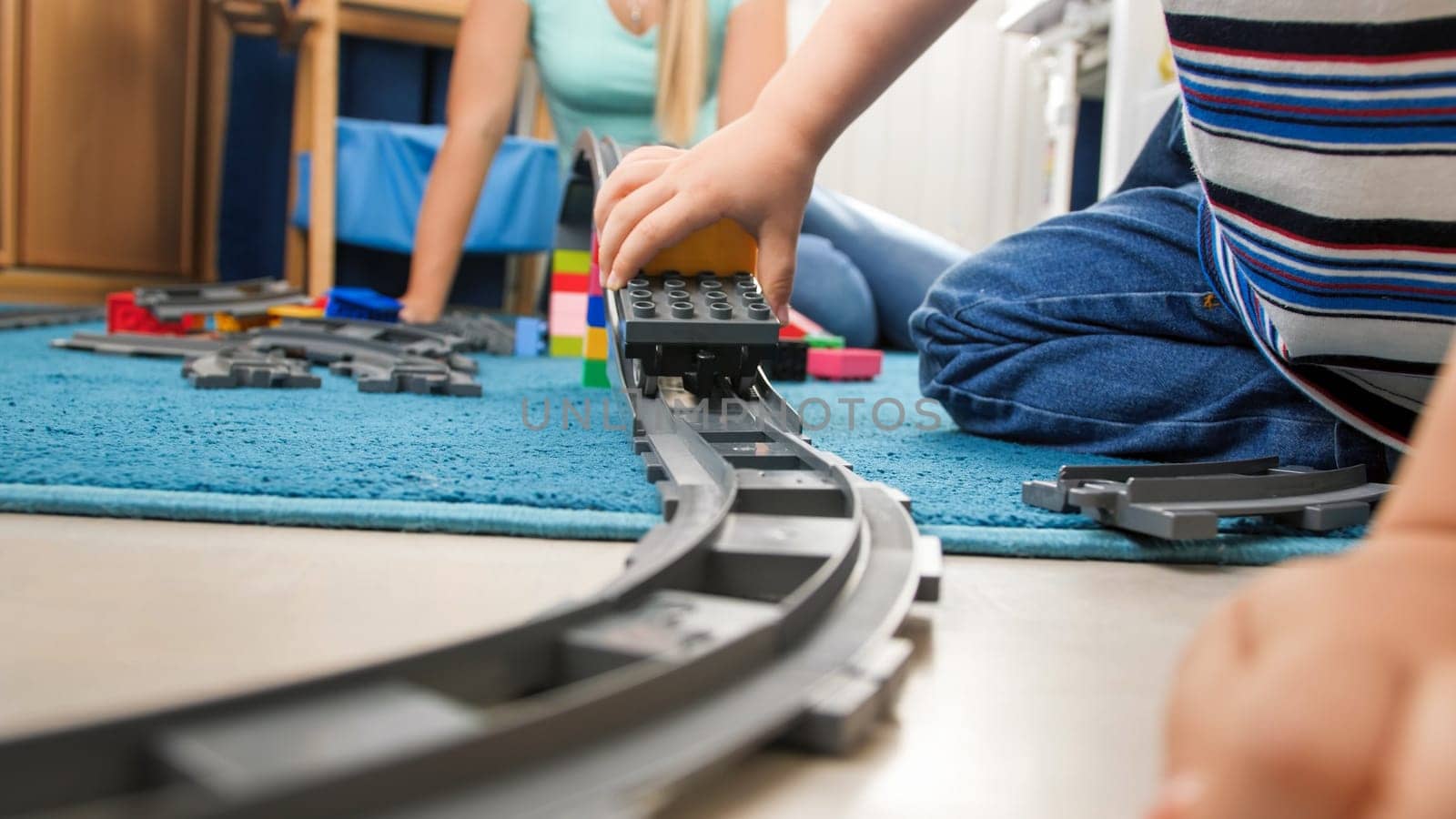 Closeup image of toy railroad with colorful train on floor at child's room.