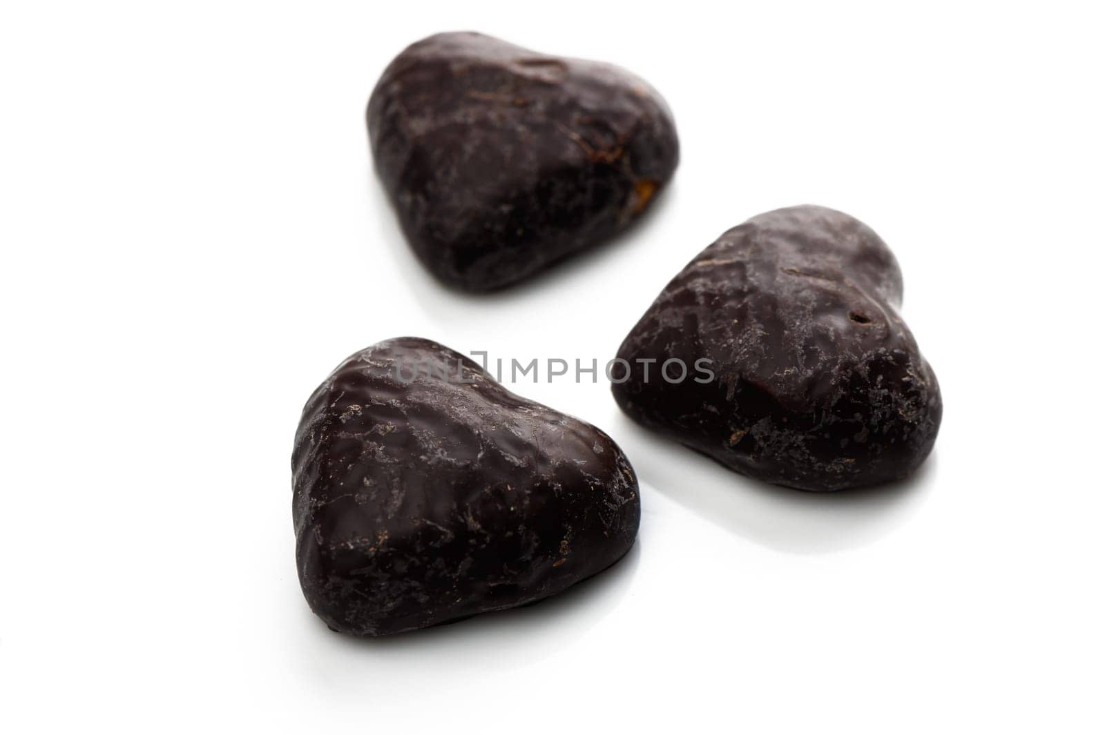 Three rich dark chocolate hearts arranged on a smooth surface, showcasing a luxurious treat for chocolate lovers.