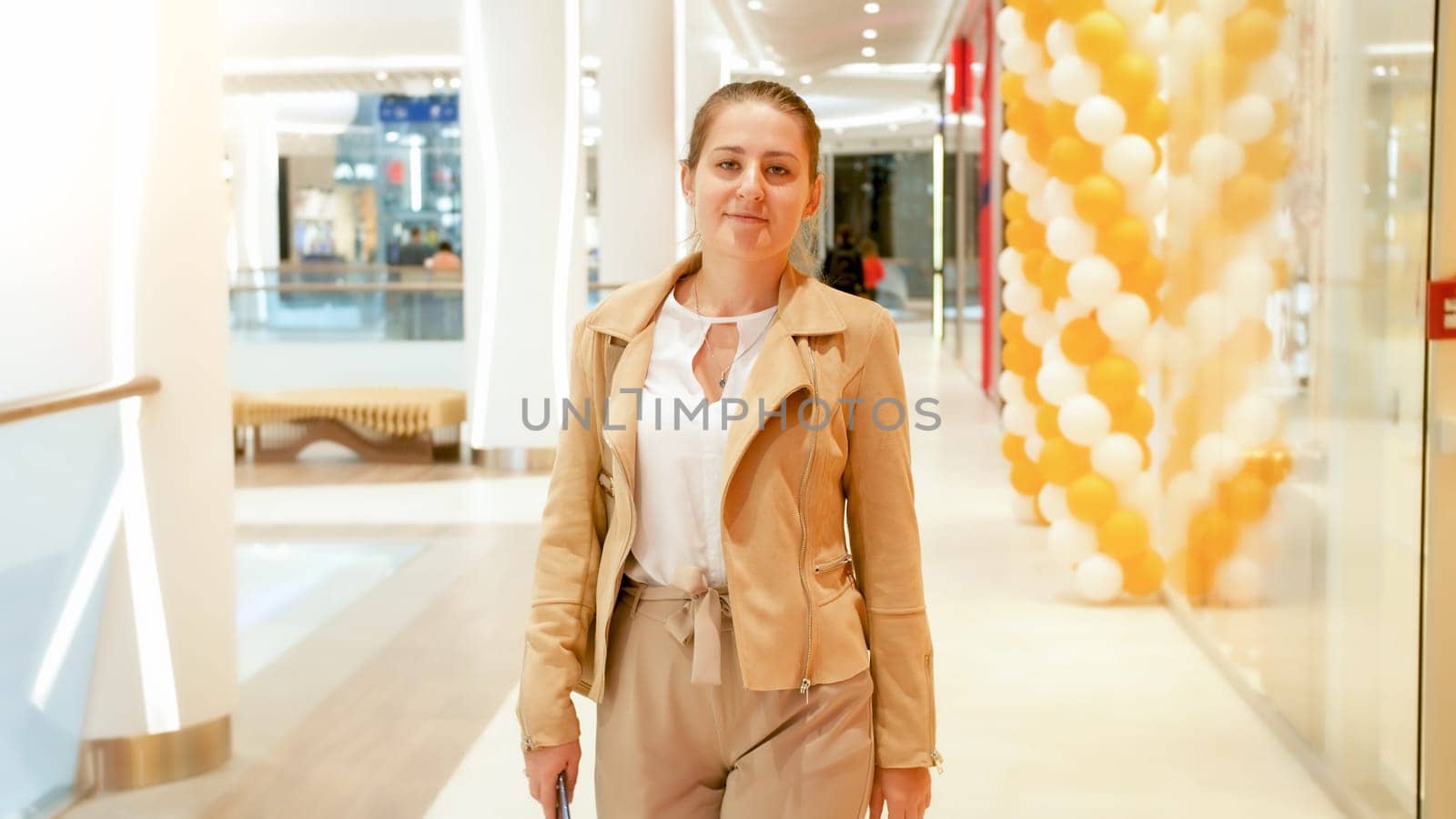 Portrait of beautiful smiling woman walking in long hallway at shopping mall.