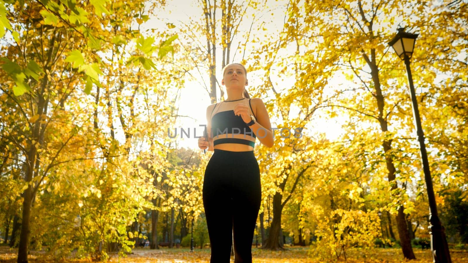 Portrait of beautiful sporty woman jogging and exercising in autumn park.