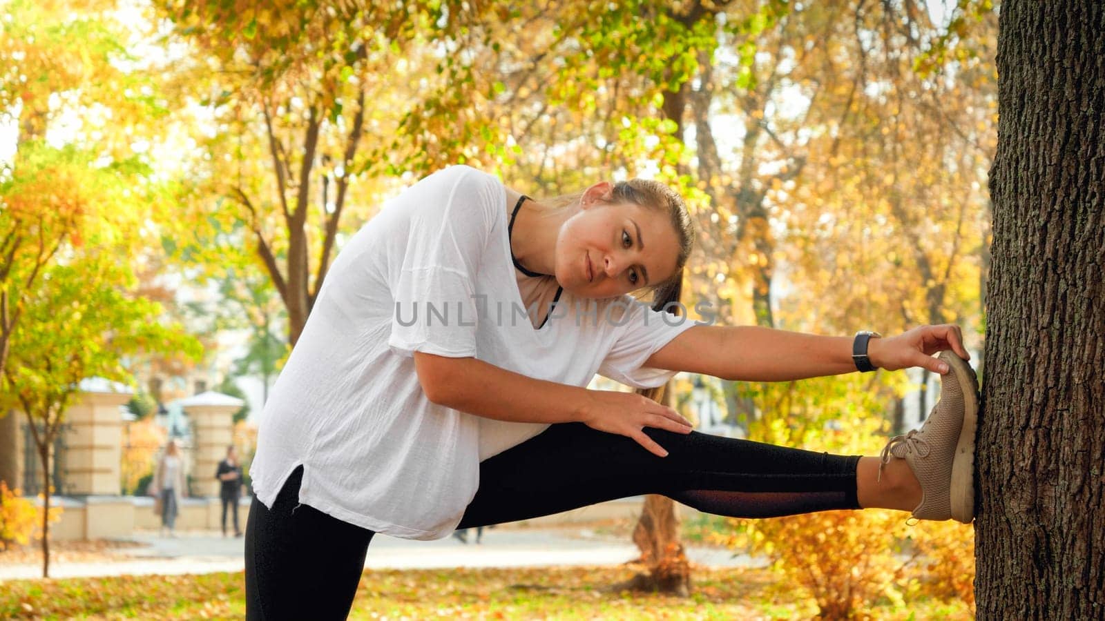 Beautiful young woman stretching and warming up before jogging in park at morning.