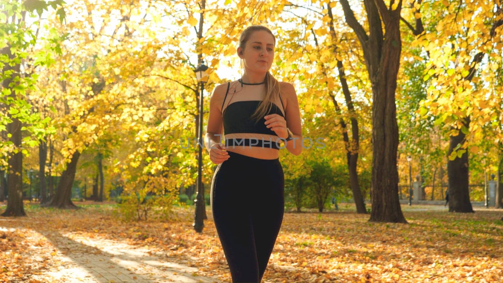 Toned portrait of young woman listening music running in autumn park.
