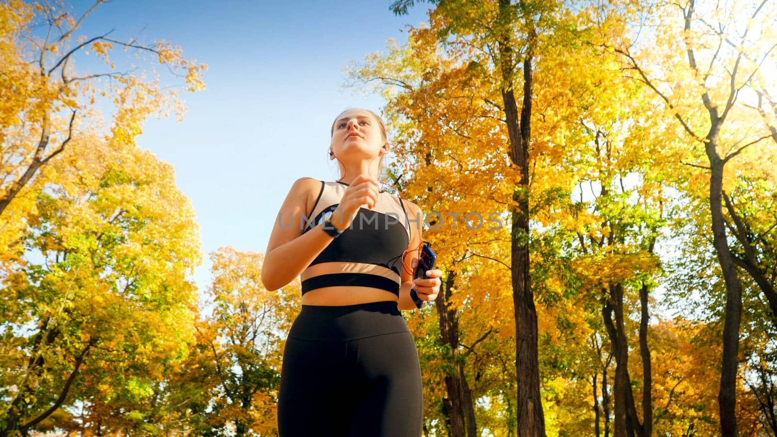 Portrait of beautiful sexy woman exercising and running in autumn park at sunrise.