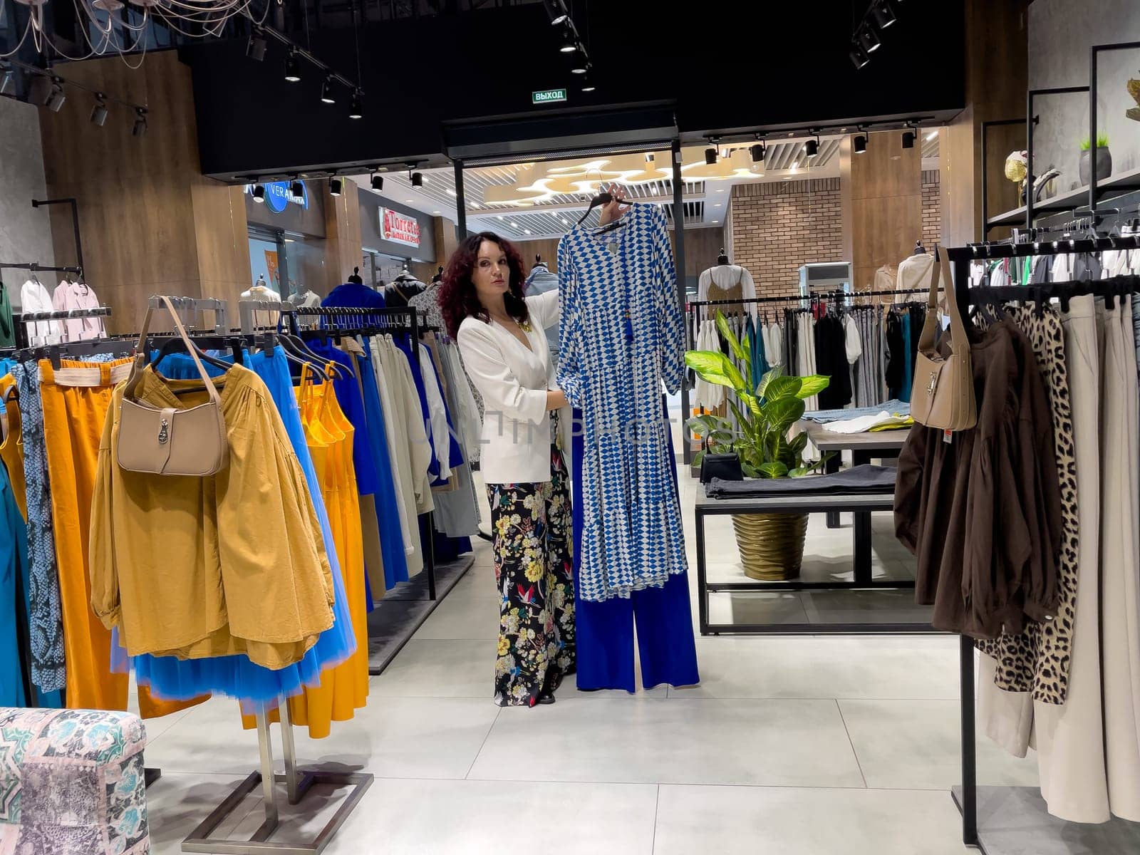 Shopping woman, women's fashion clothes in a store, boutique. Woman choosing clothes in a store.