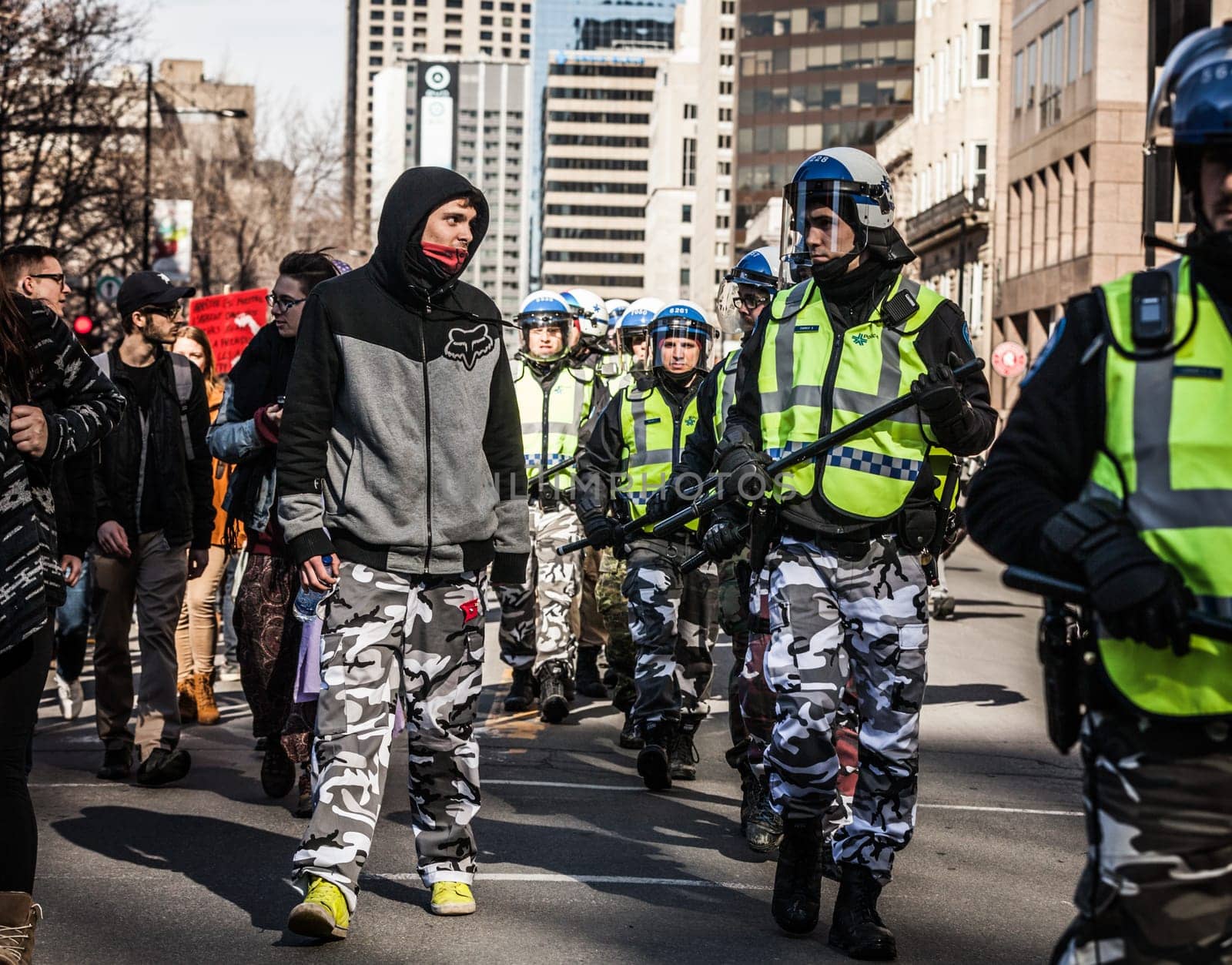 MONTREAL, CANADA, APRIL 02 2015. Riot in the Montreal Streets to counter the Economic Austerity Measures. Policeman and Protester looking each other in the eyes and wearing the same Army Pants