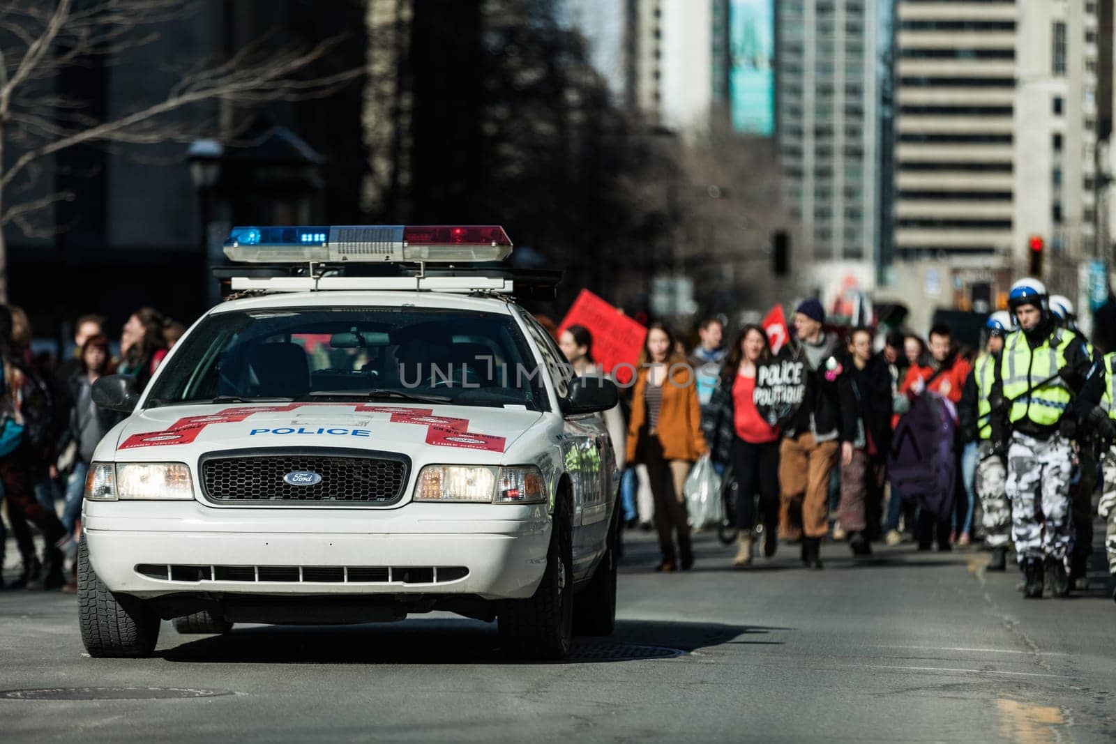 MONTREAL, CANADA, APRIL 02 2015. Riot in the Montreal Streets to counter the Economic Austerity Measures. Police Car in front of the Protesters controlling the Traffic