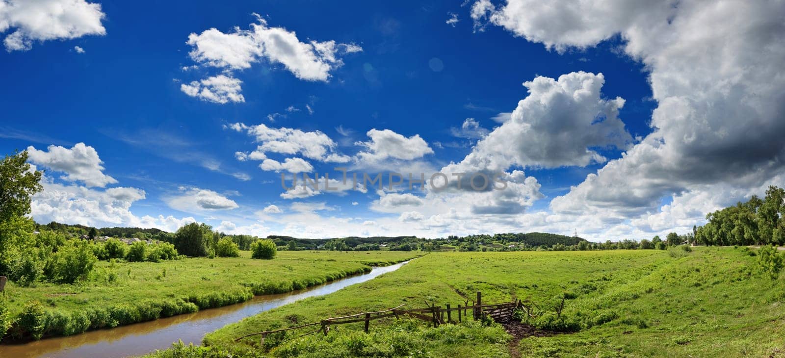 wonderful panoramic landscape of the sunny river valley with blue sky and clouds