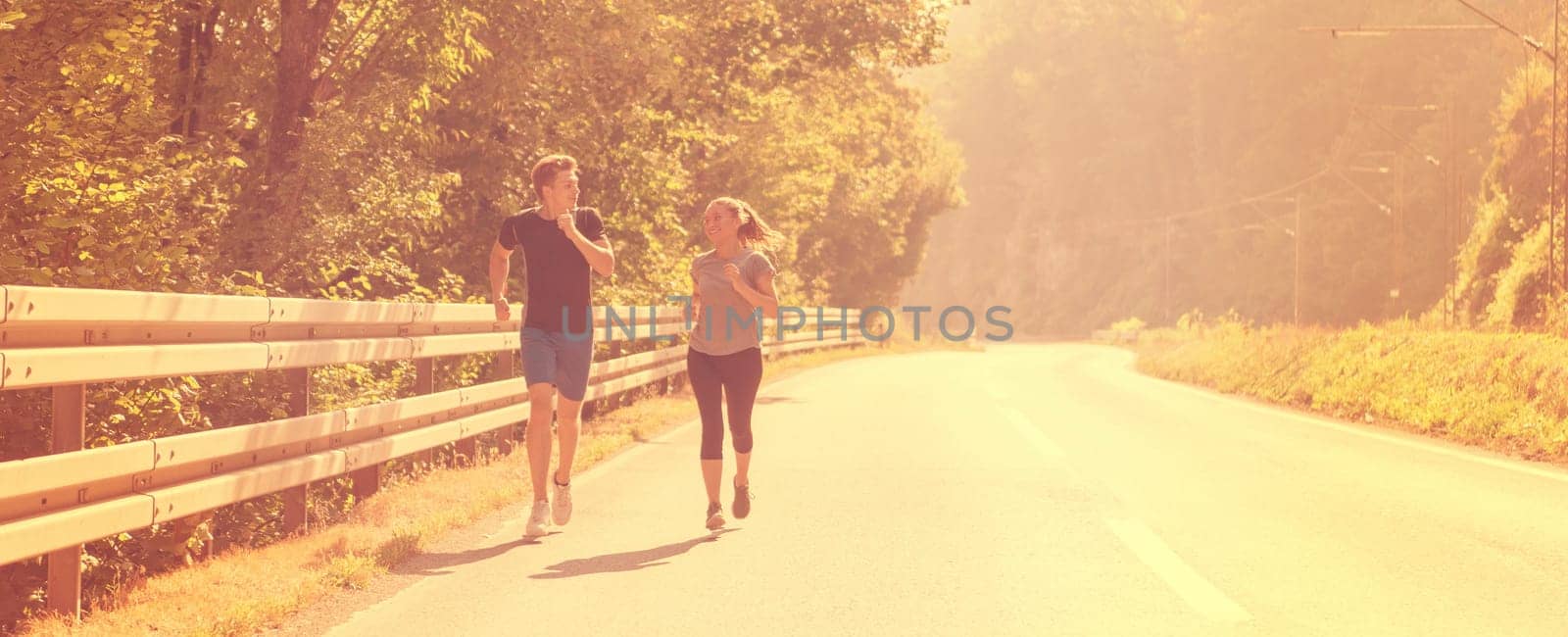 young couple enjoying in a healthy lifestyle while jogging along a country road, exercise and fitness concept