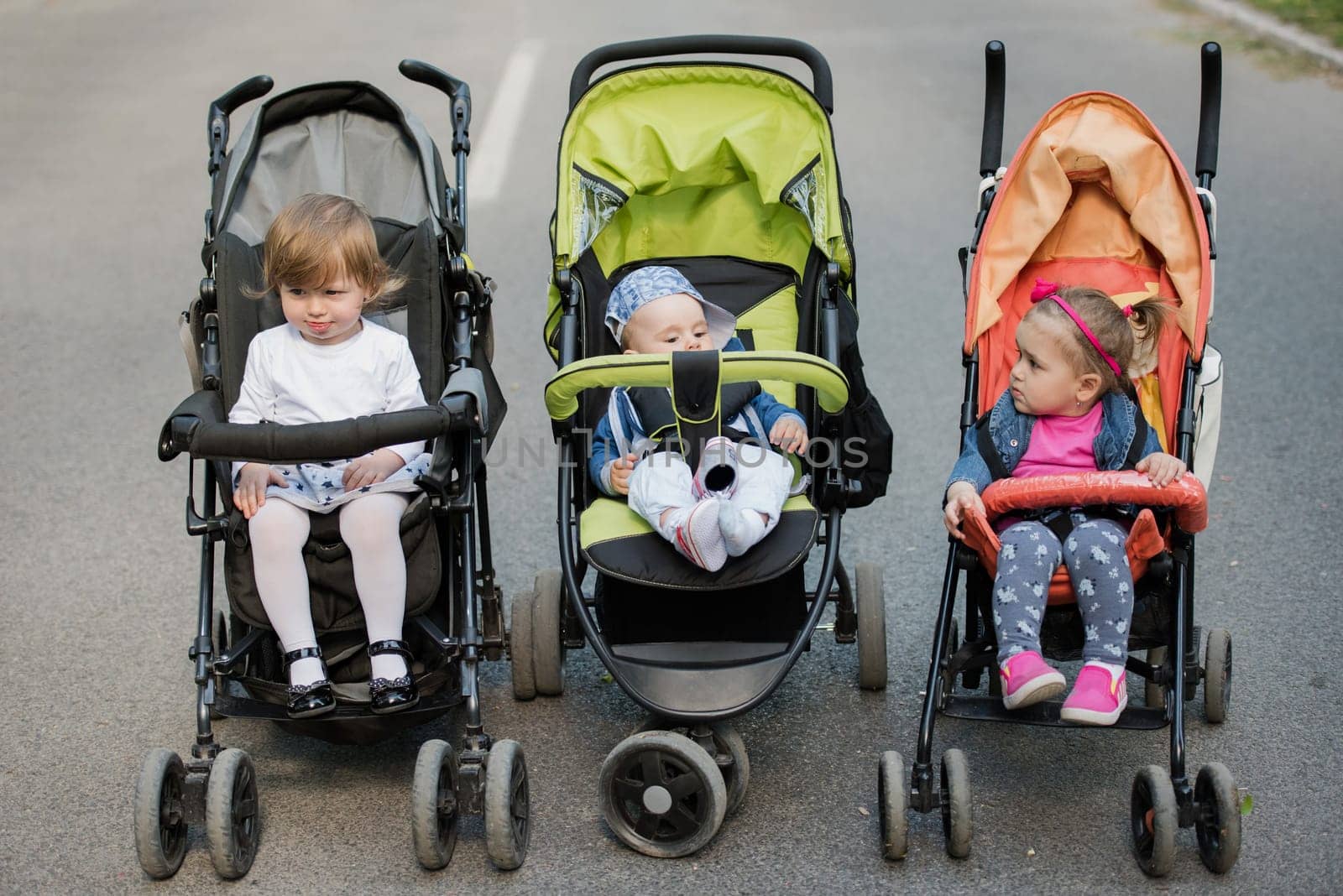 beautiful babies sitting in a stroller in the park