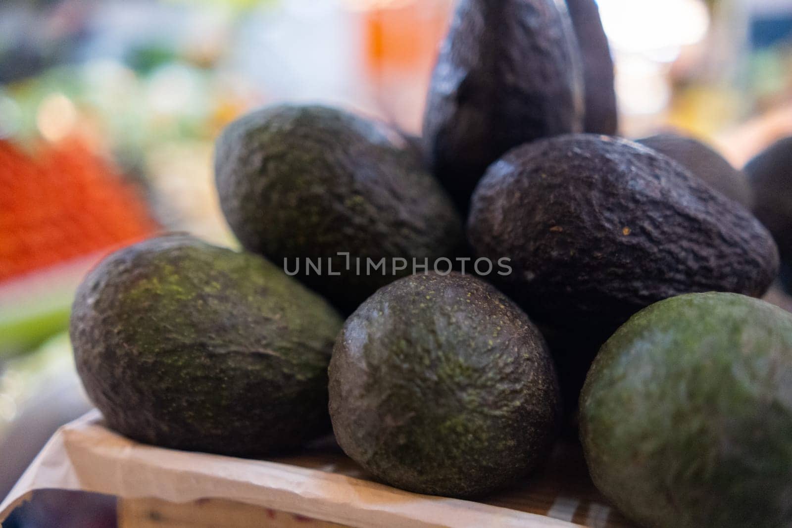 Close-up of pile of fresh avocados with blurry background. Classic Mexican vegetables for sale in market. Natural healthy food