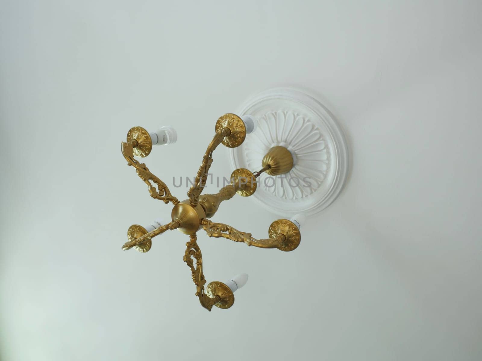 bronze vintage chandelier on the ceiling with stucco rosette overhead