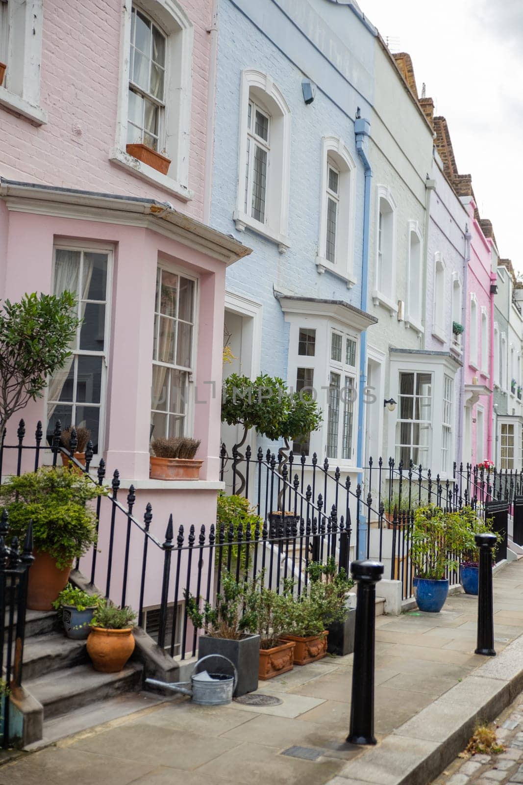 Row of small colorful British houses with handrails and plants. Beautiful pastel colors English houses with victorian architecture. Peaceful London neighborhood