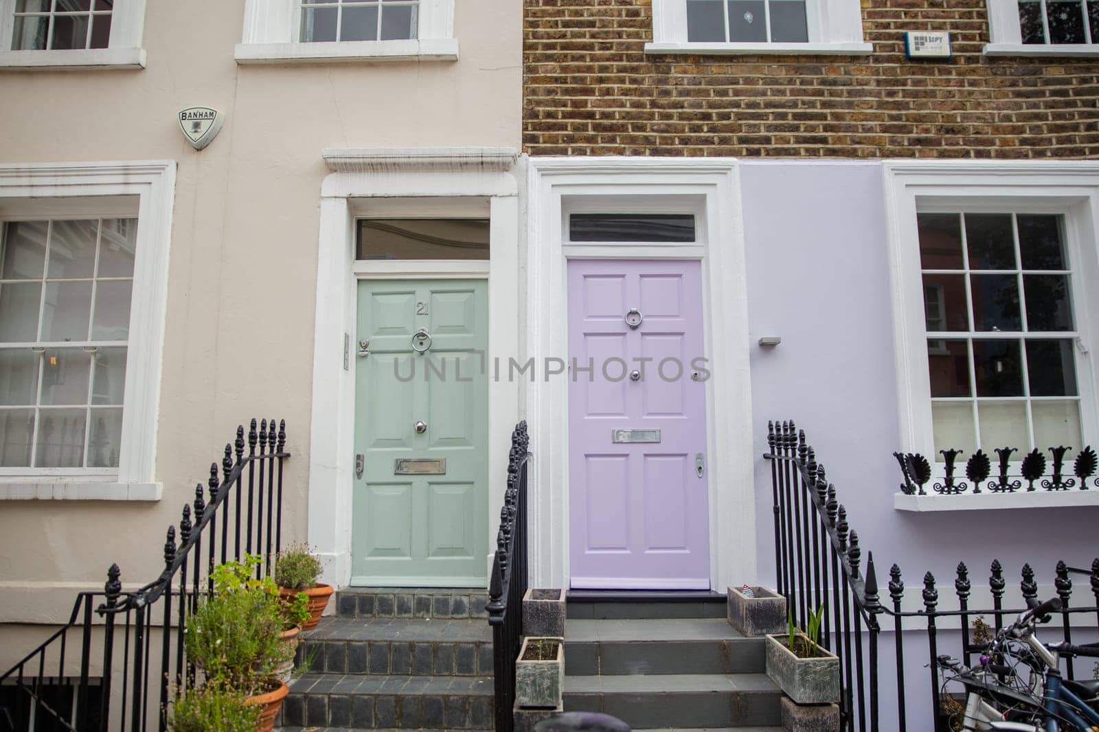 Colorful British houses with plants and handrails outside. Beautiful English houses with pastel colors and Victorian architecture. Peaceful London neighborhood