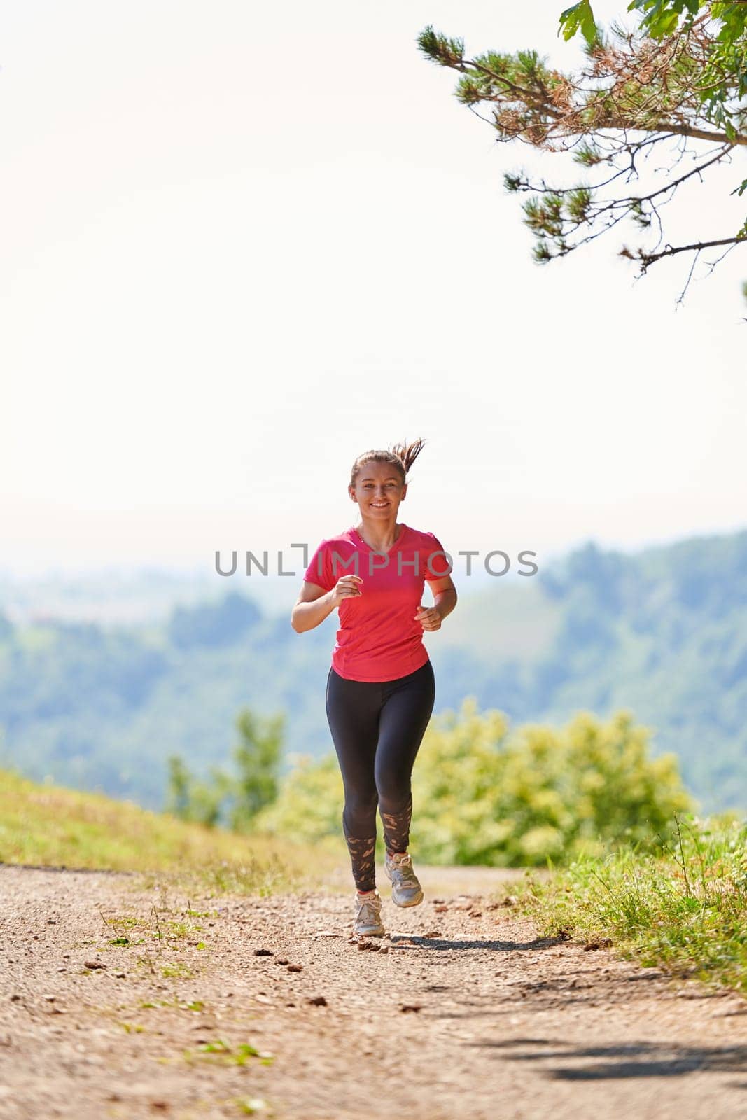 woman enjoying in a healthy lifestyle while jogging on a country road through the beautiful sunny forest, exercise and fitness concept