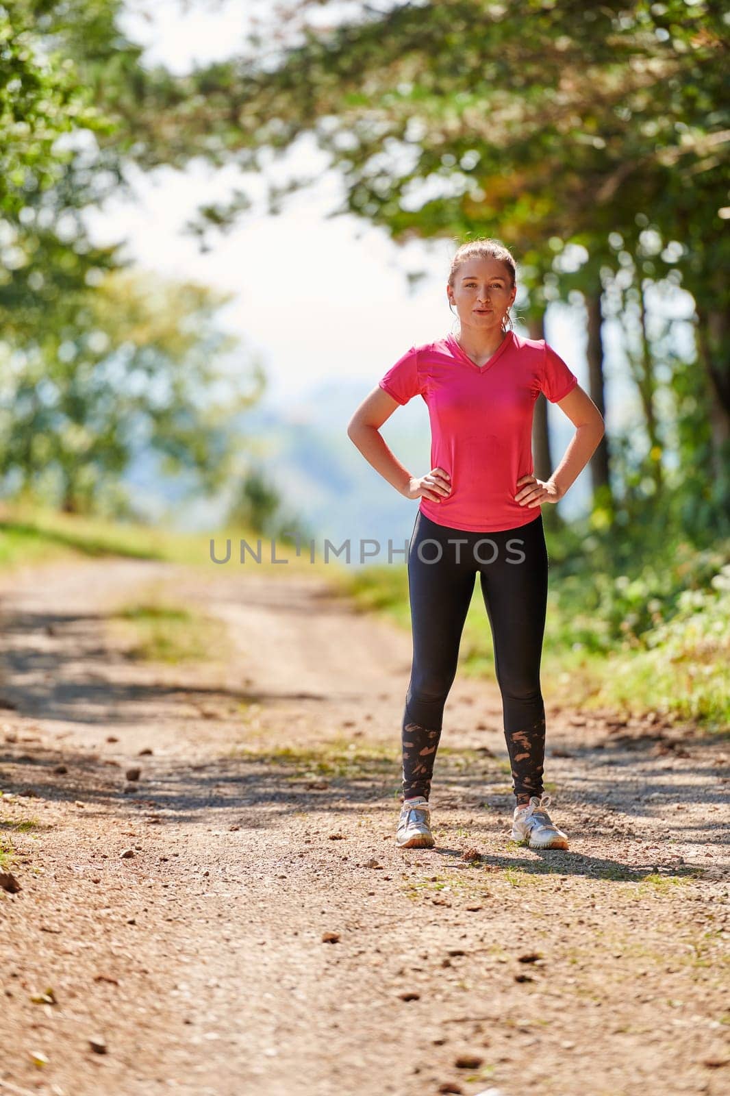 woman enjoying in a healthy lifestyle while jogging on a country road through the beautiful sunny forest, exercise and fitness concept