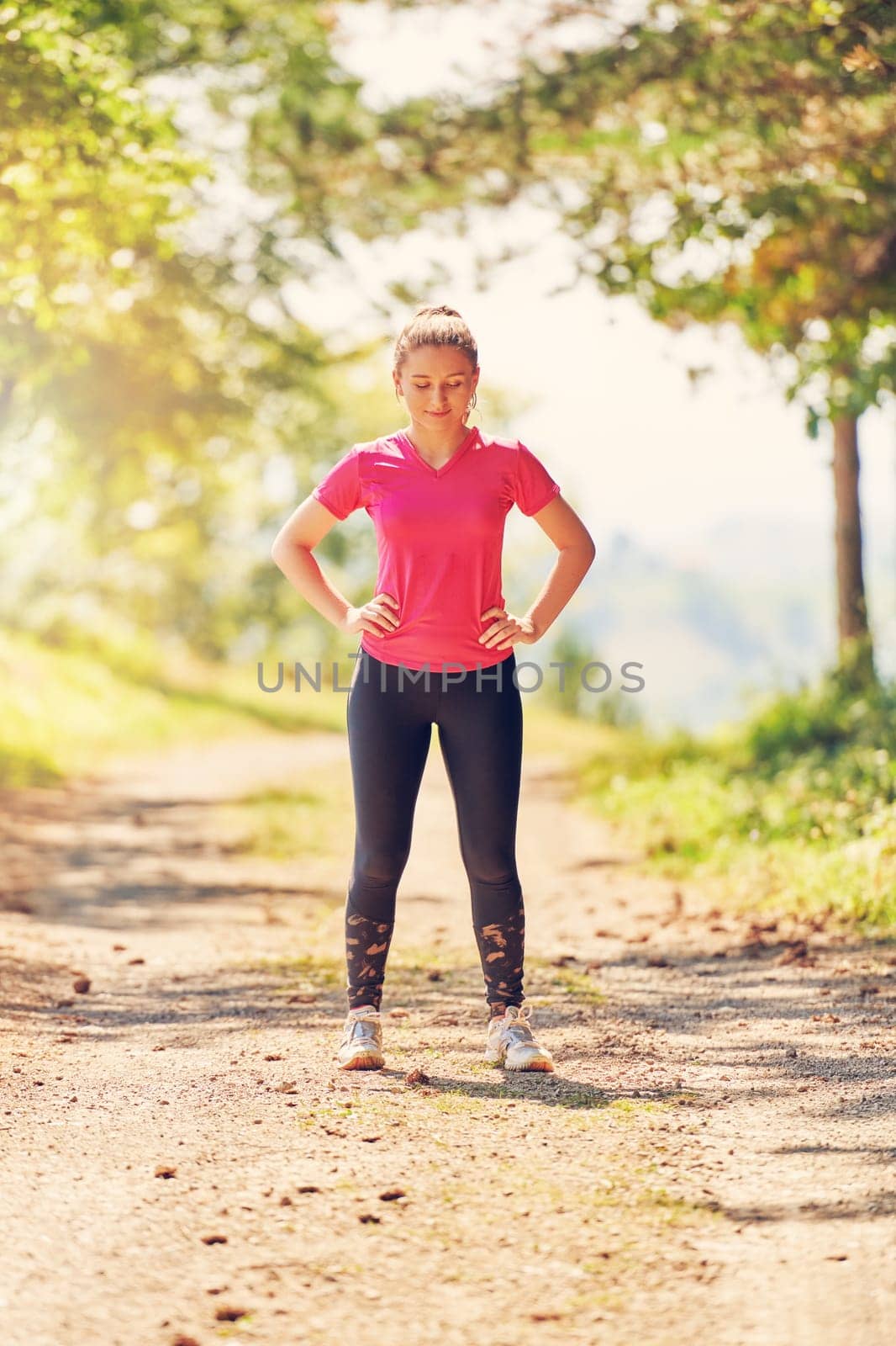 woman enjoying in a healthy lifestyle while jogging on a country road through the beautiful sunny forest, exercise and fitness concept