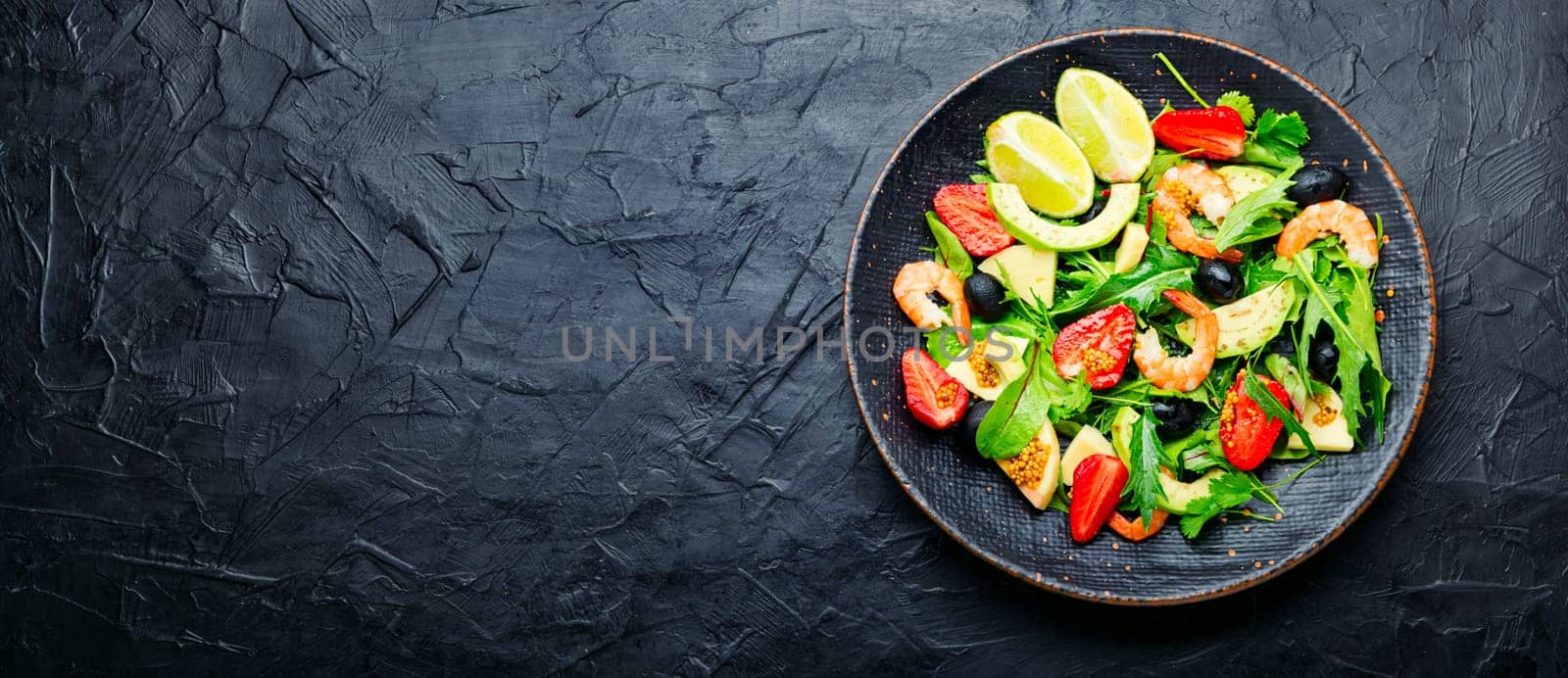 Diet salad with shrimps,strawberries and avocado.Salad in a stylish metal plate