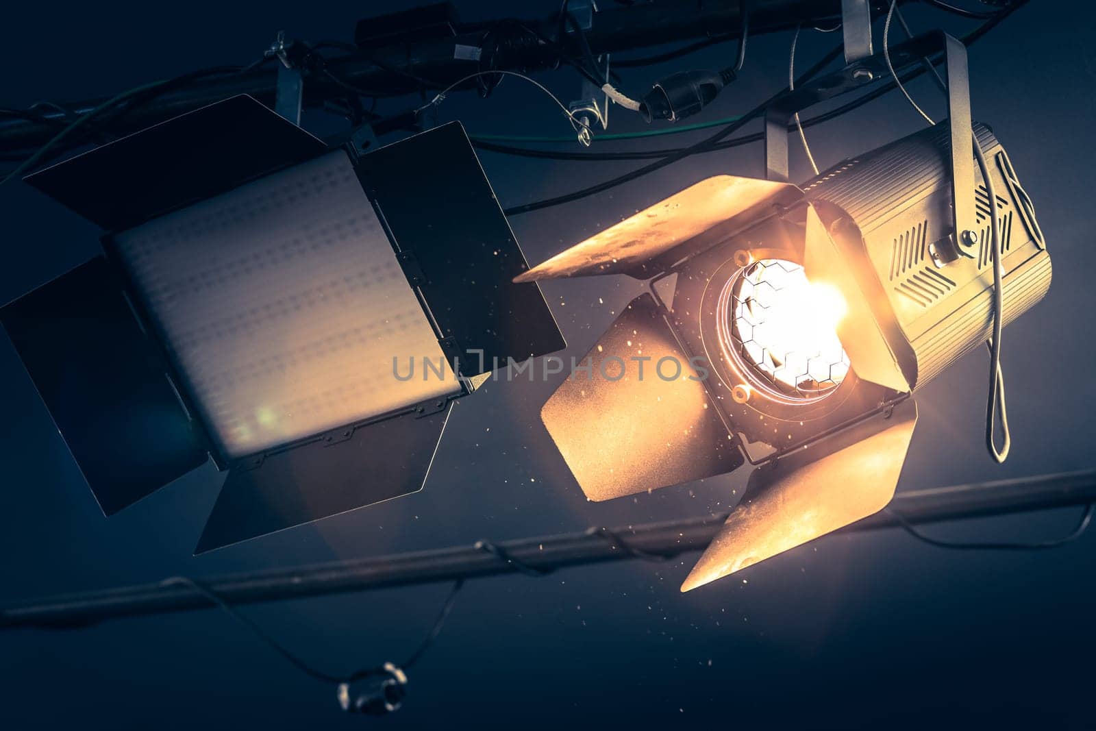 Professional orange studio spotlight hanging on the ceiling. Lighted dust particles and lens flares.