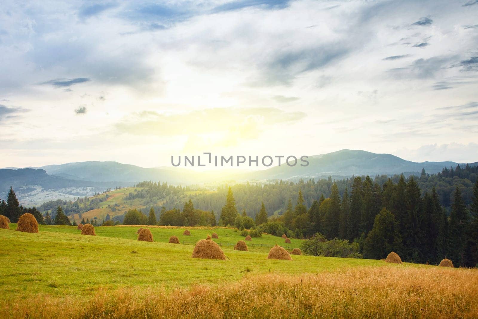 Summer mountain village view with stacks of straw