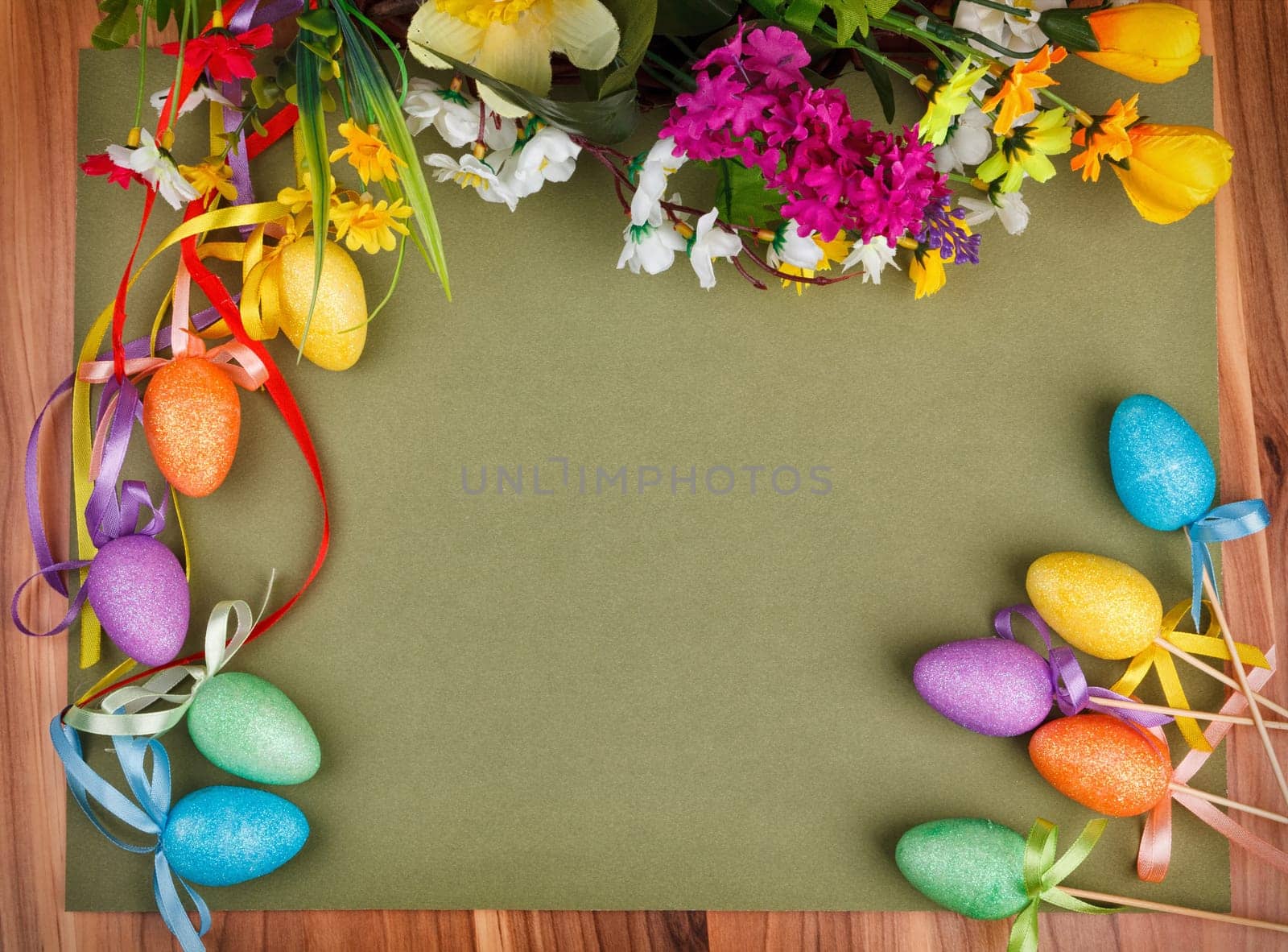 Easter flower arrangement and colorful eggs on green background with space for text