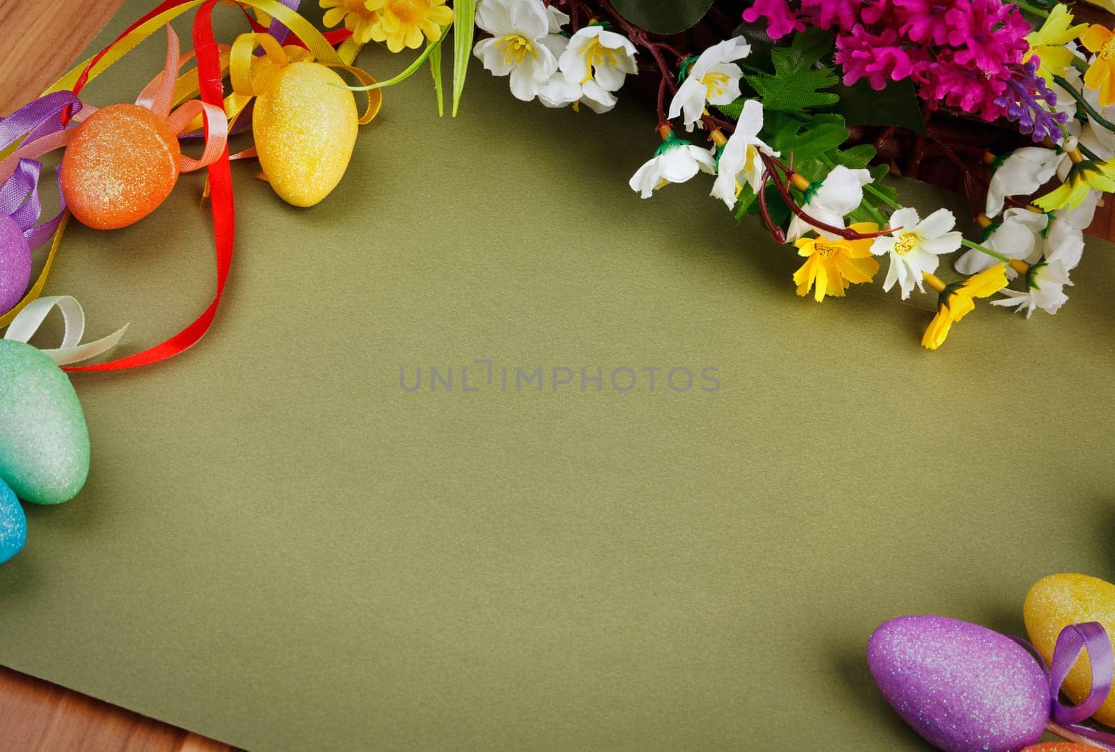 Easter flower arrangement and colorful eggs on green background with space for text