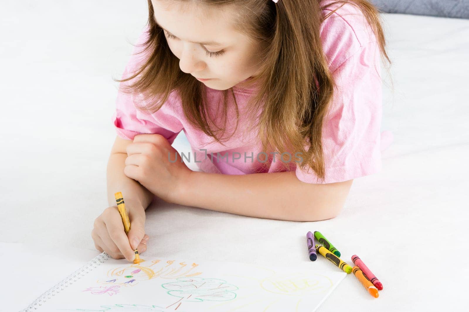 The girl draws lying on the floor