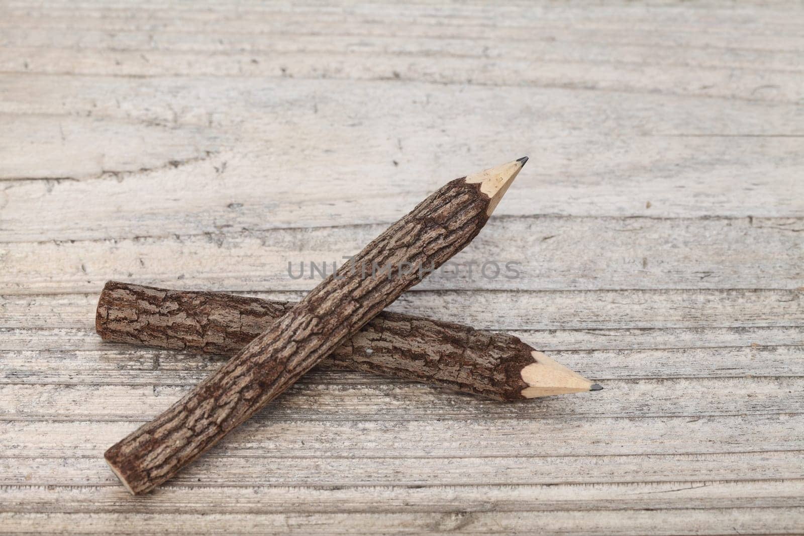 Tree trunk pencils on wooden background