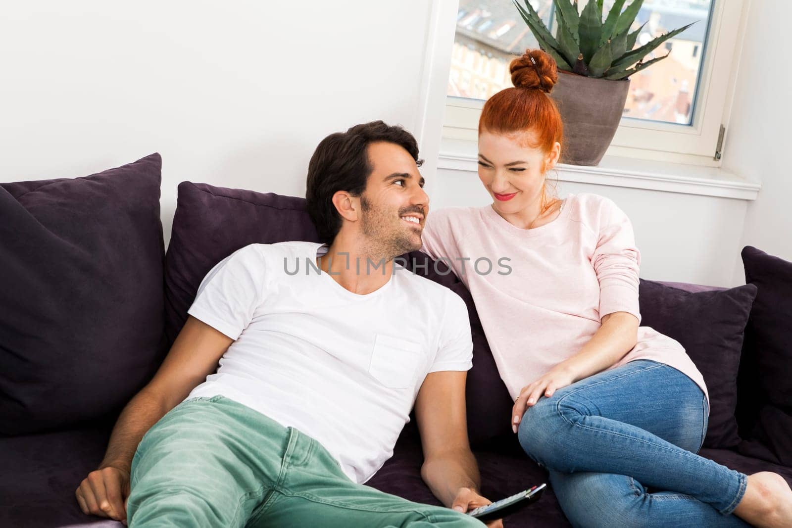 Happy young couple sit at home in the living room on the couch and cuddle in love