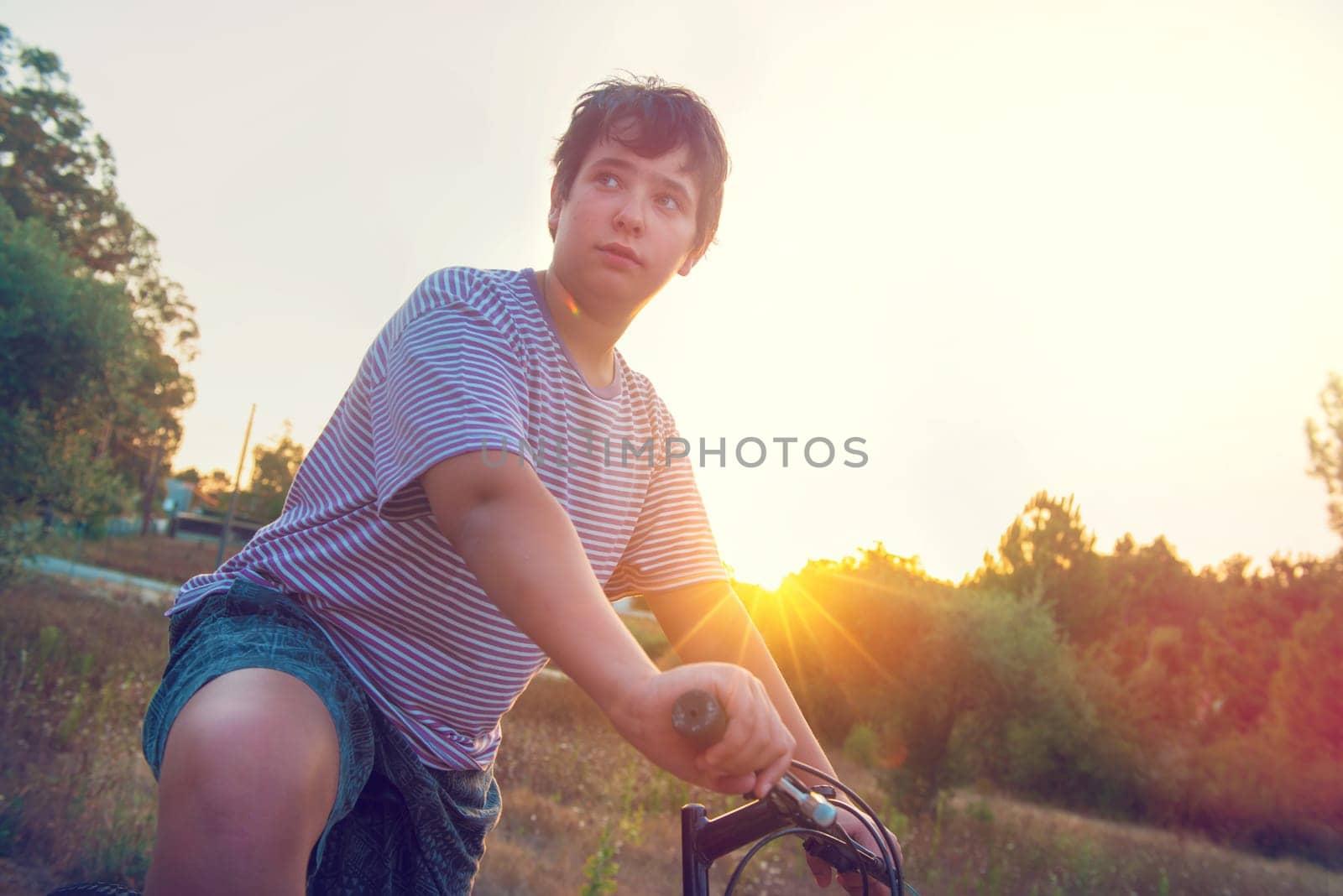 Happy boy posing in a bicycle outdoors at sunset