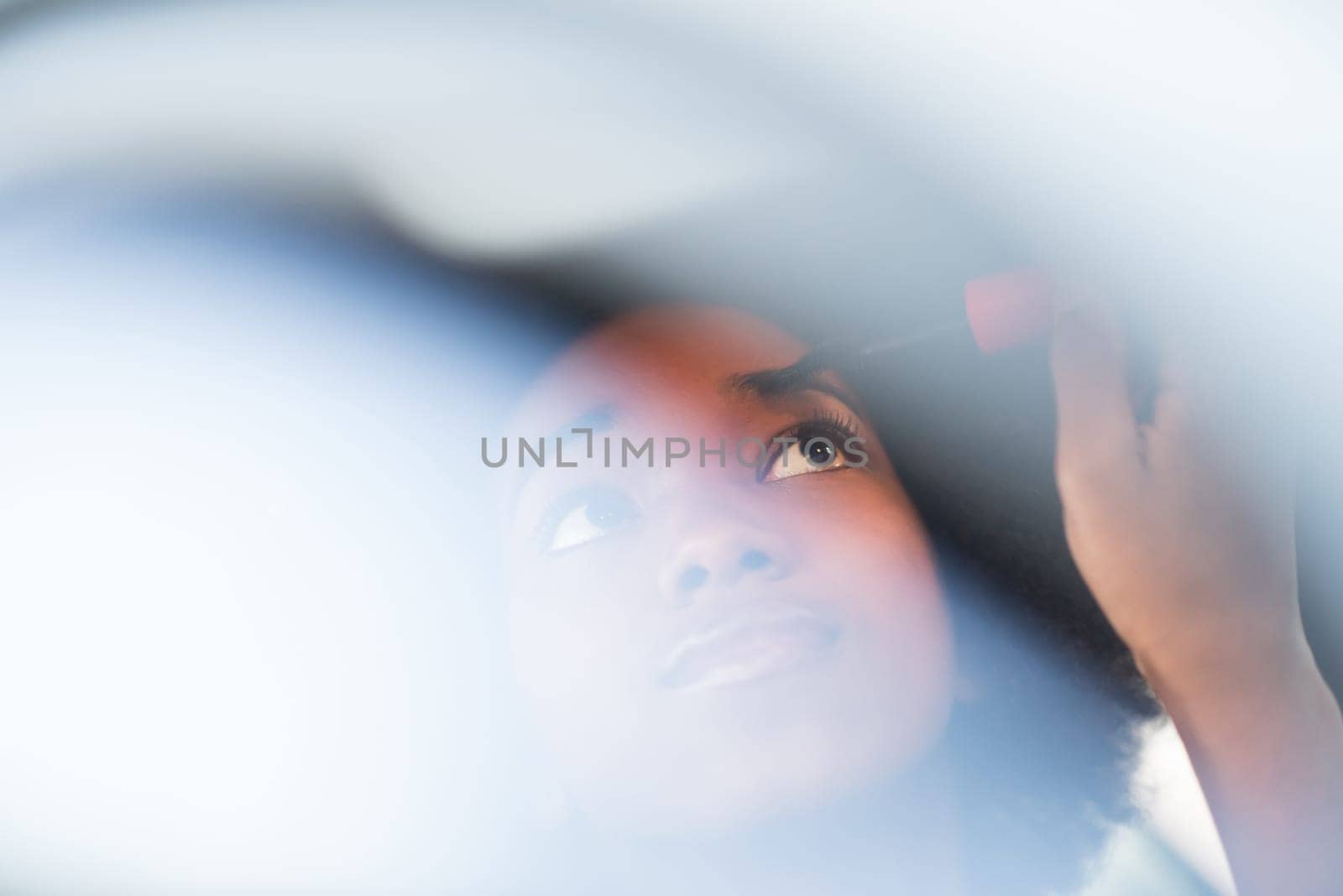 young beautiful African American woman making makeup while driving car
