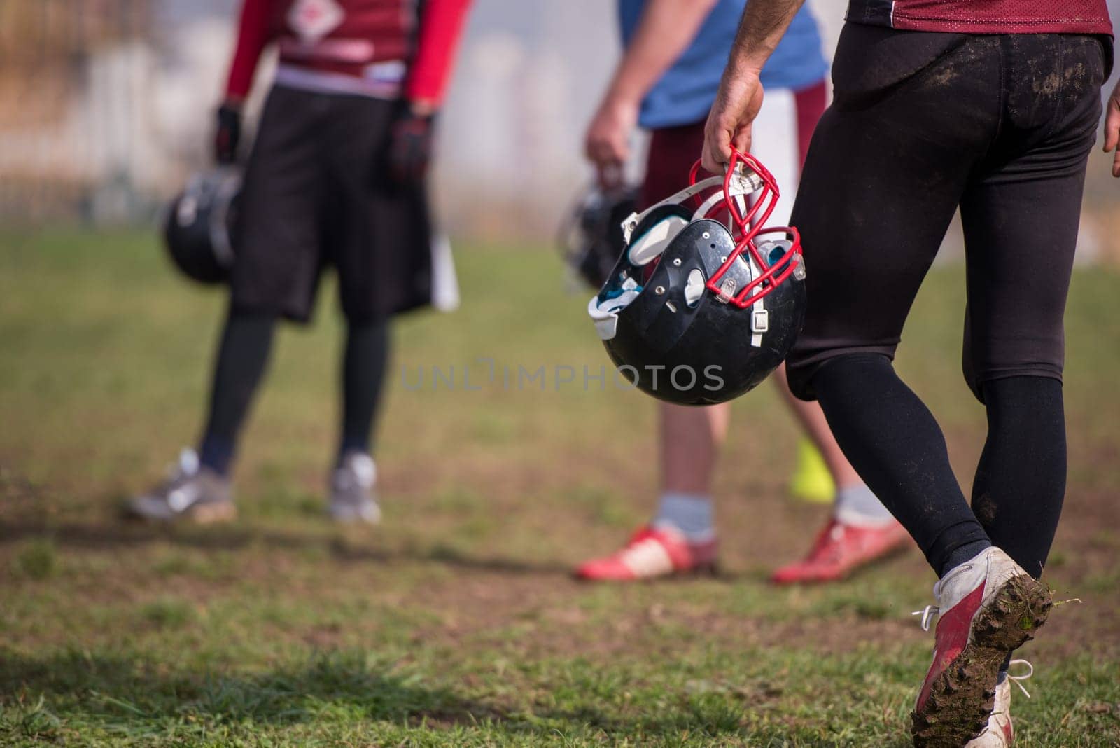 closeup shot of American football player holding black helmet at field