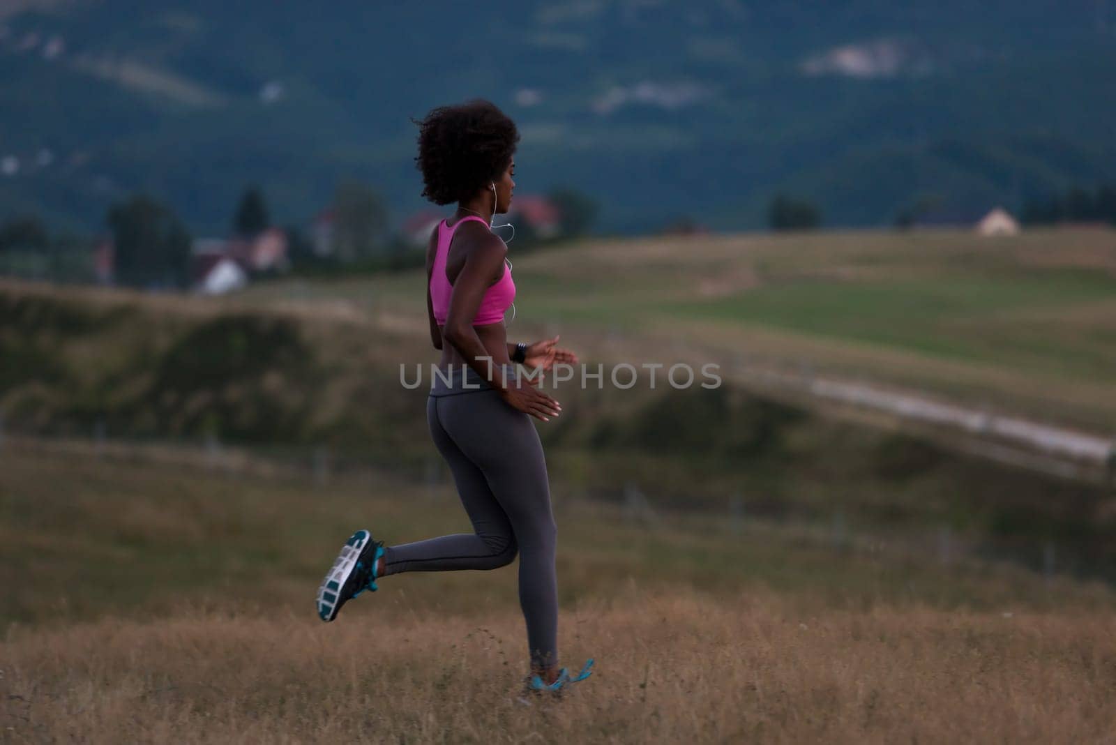 young African american woman runner with headphones jogging outdoors in nature beautiful summer night - Fitness, people and healthy lifestyle