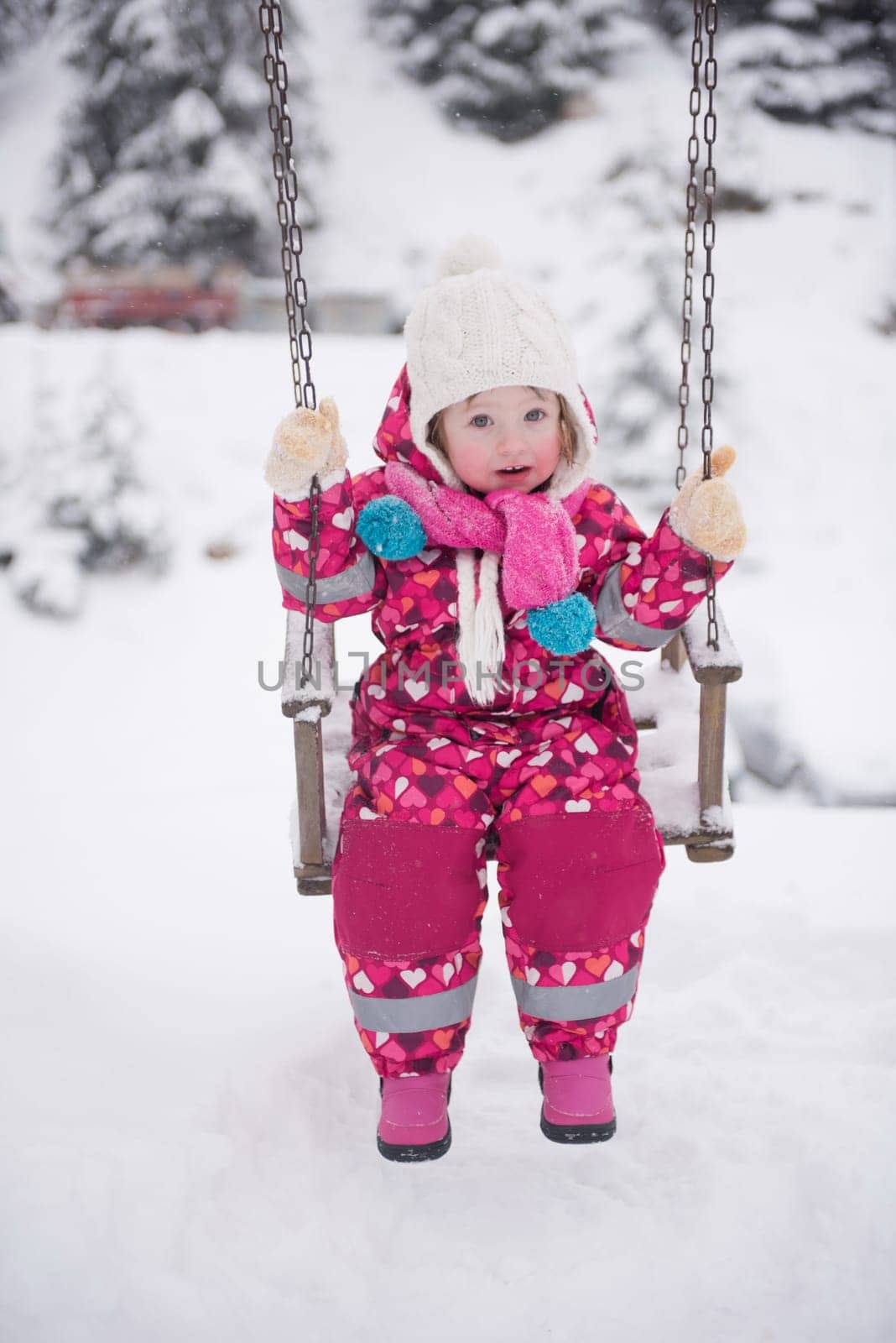 child outdoor in park at winter day with fresh snow, cute little girl swing and playing