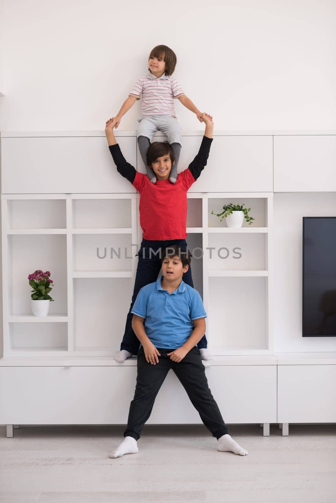 happy young boys having fun and posing line up piggyback in new modern home