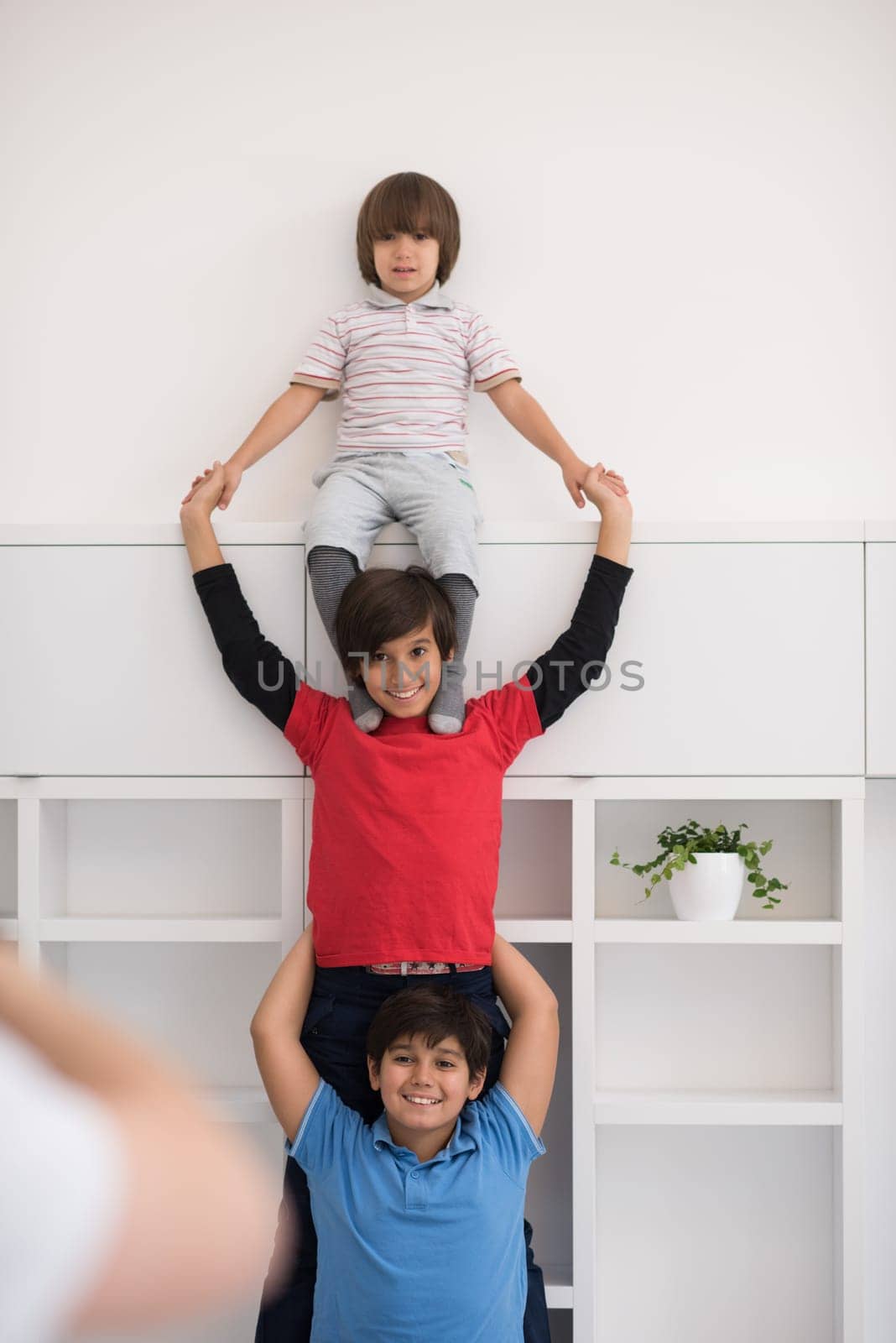 happy young boys having fun and posing line up piggyback in new modern home