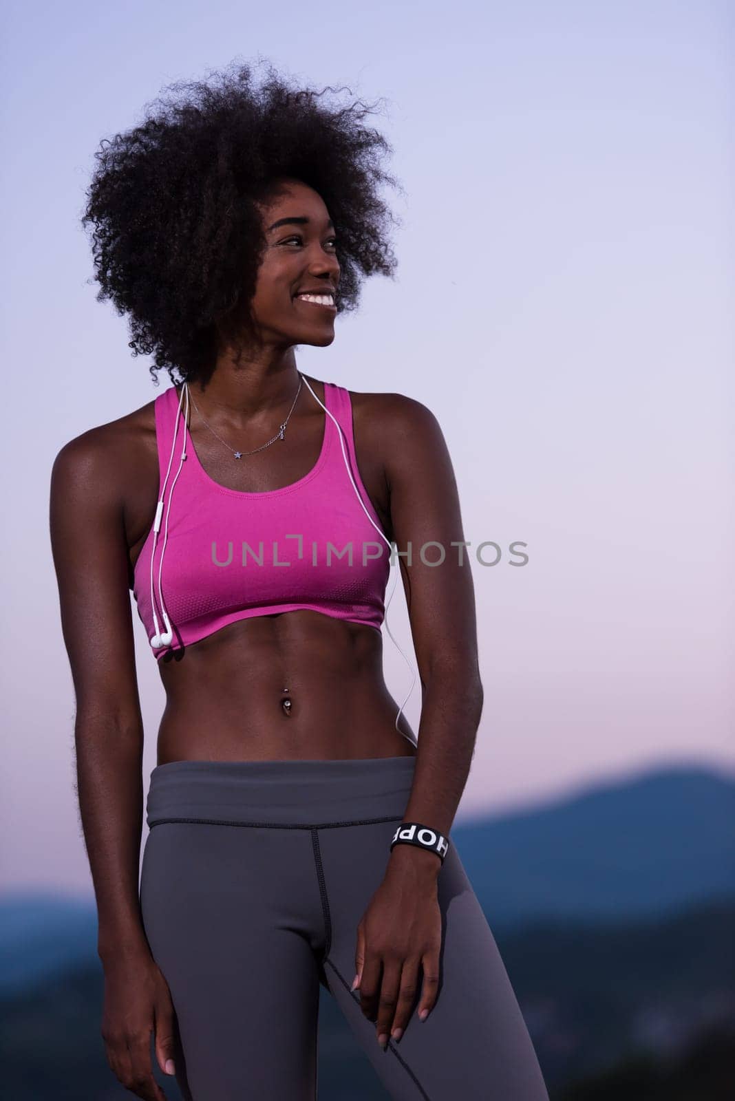 portrait of a young beautiful african american woman with headphones jogging in nature beautiful summer night