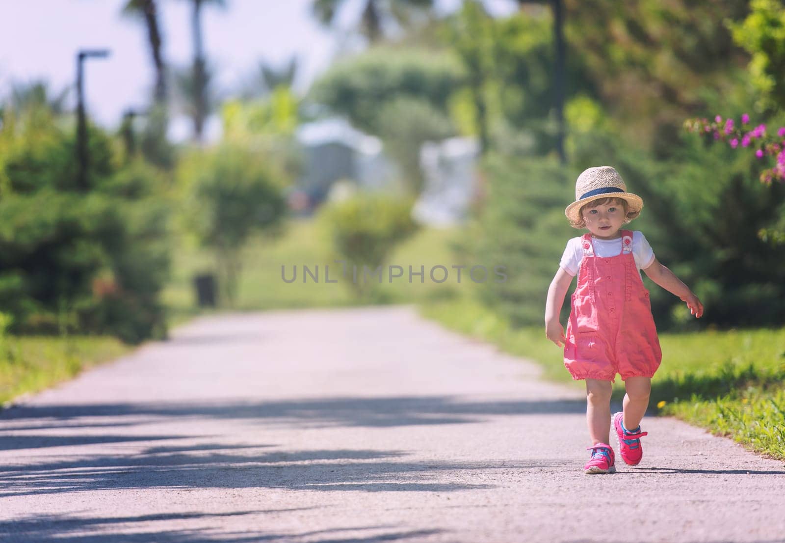cute little girl with hat cheerfully spending time while running at Park on the summer morning