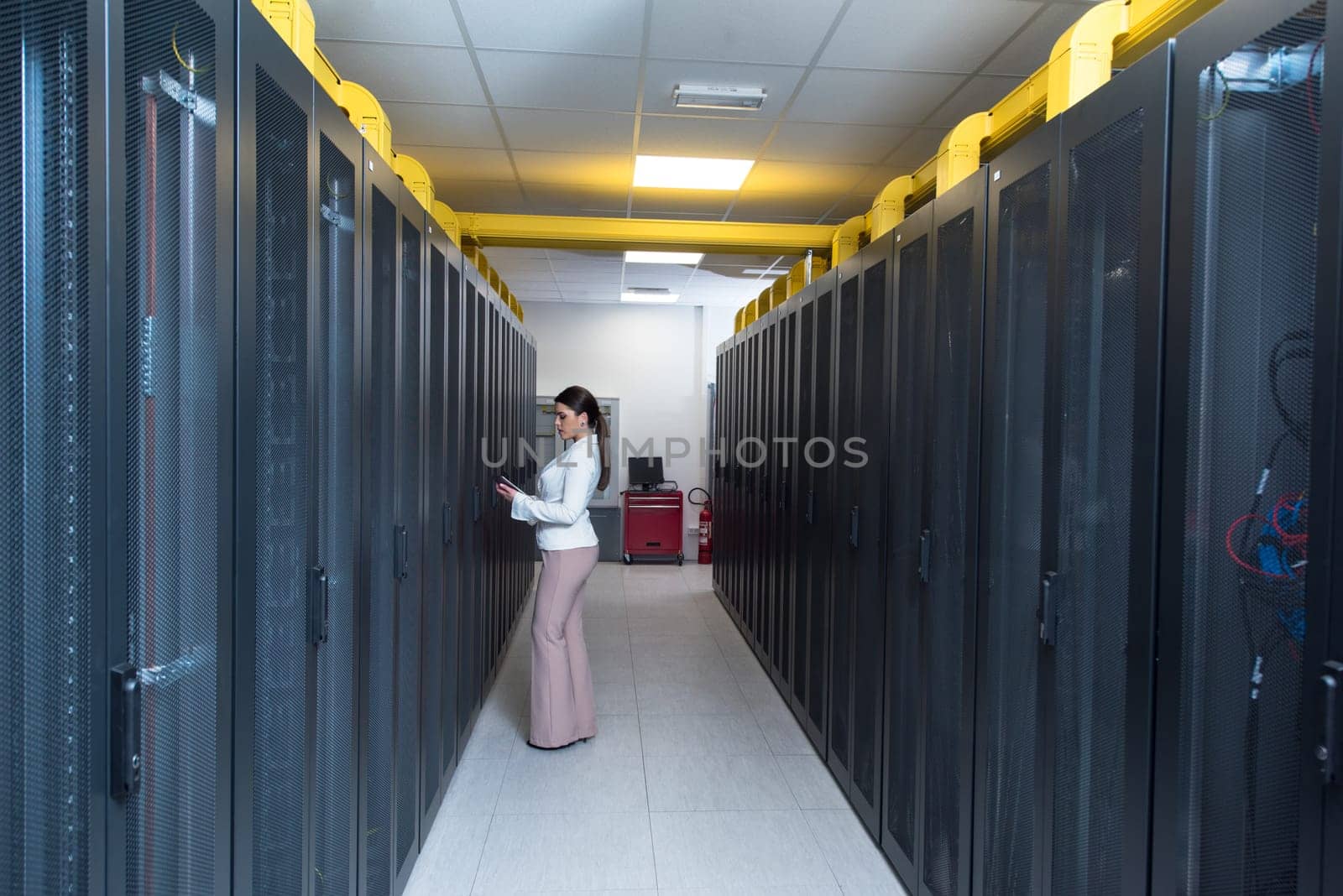 Female IT engineer working on a tablet computer in server room at modern data center