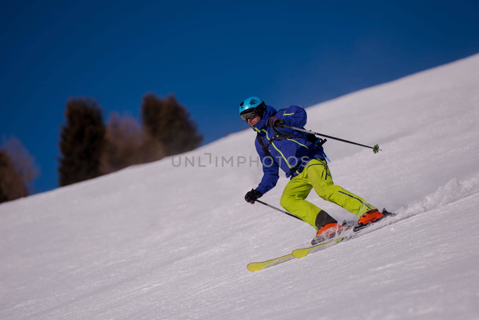 young athlete freestyle Skier having fun while running downhill in beautiful Alpine landscape on sunny day during winter season