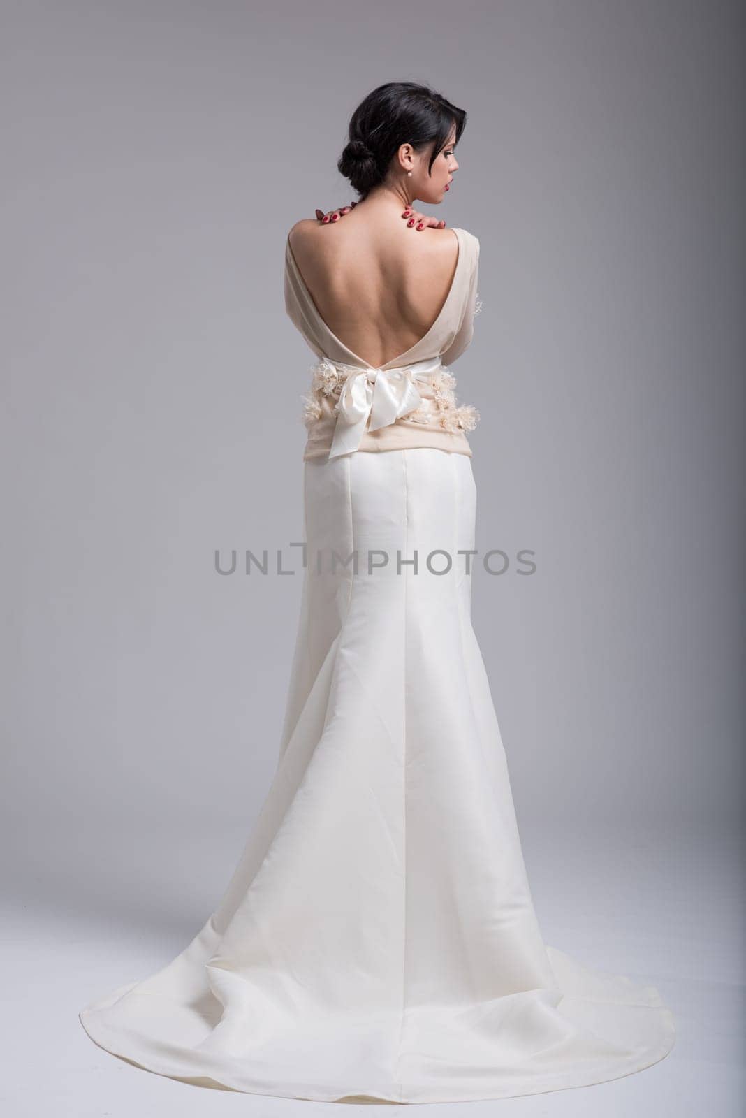 Rear view of a beautiful young bride in a wedding dress isolated on a white background