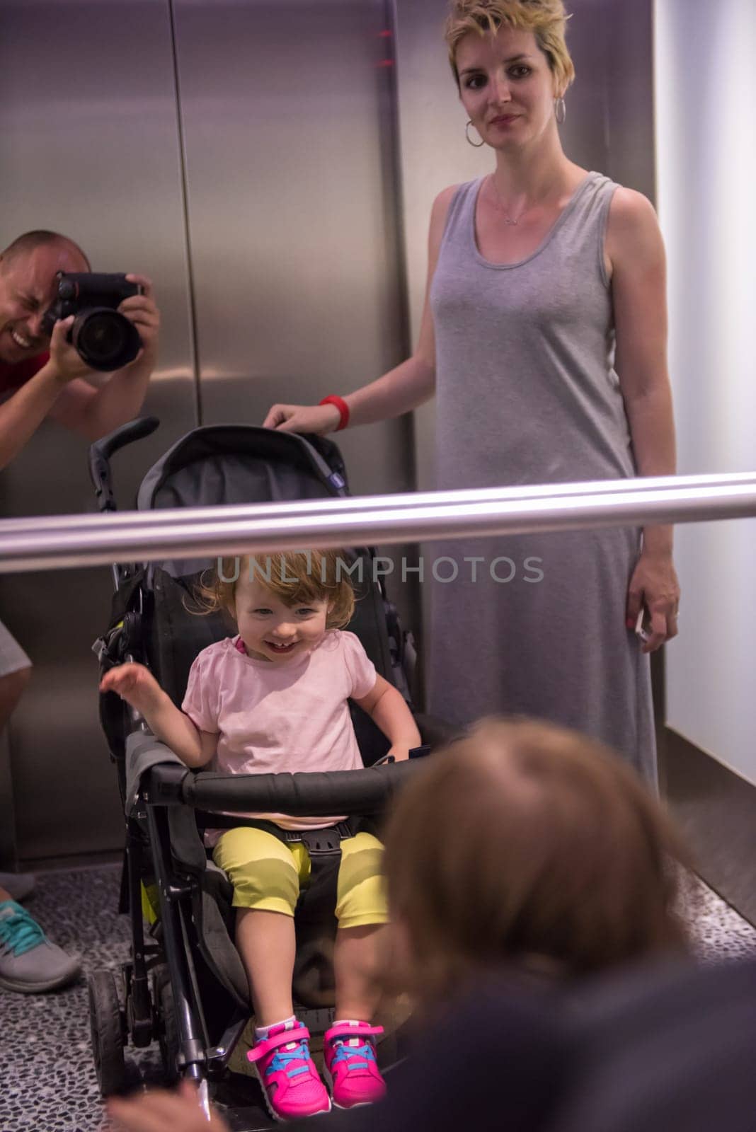 young father taking pictures of his happy family in the mirror of the elevator
