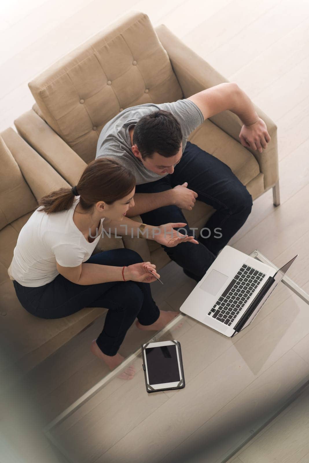 happy young couple buying online using laptop a computer and a credit card in their luxury home villa