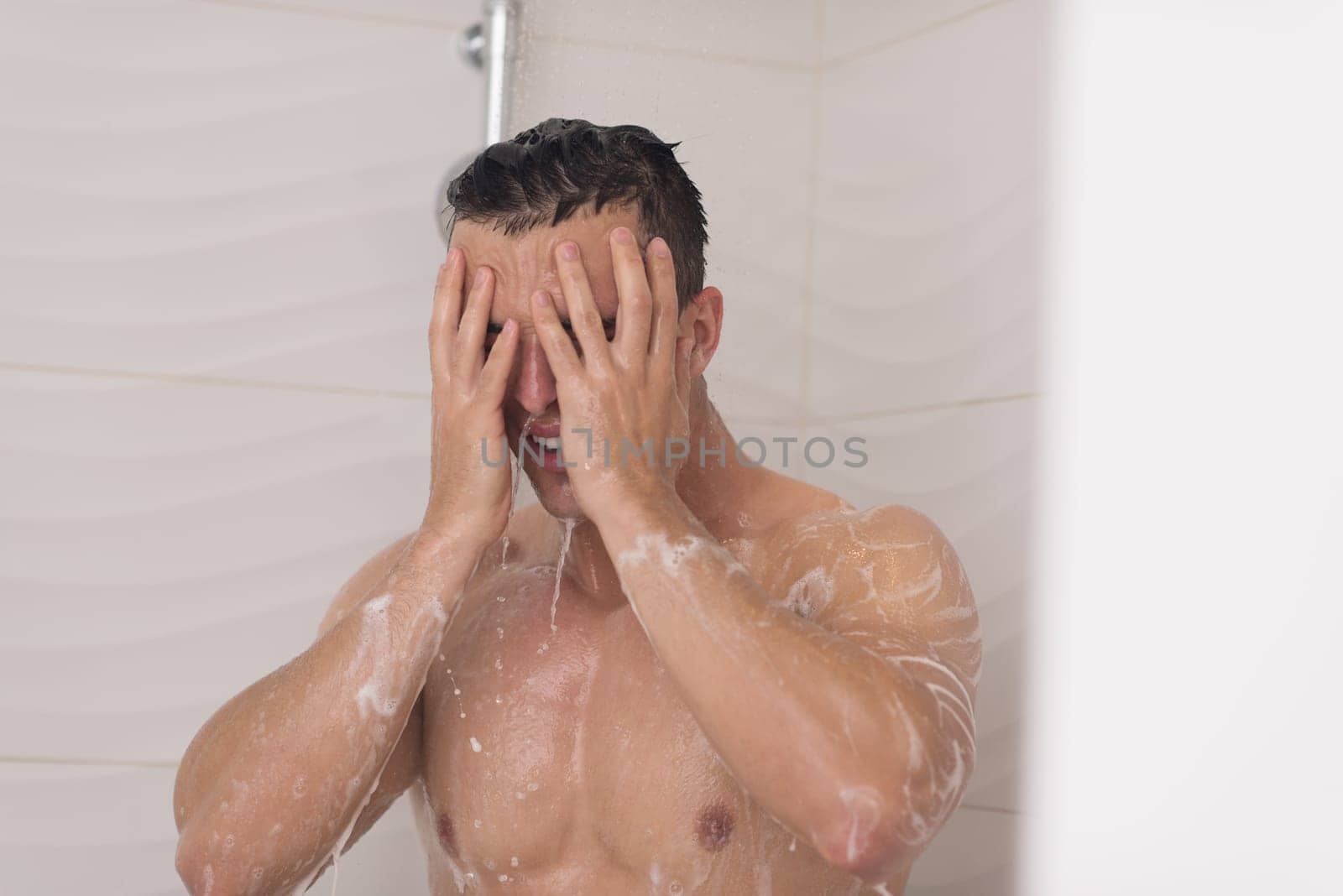 young good looking and attractive man with muscular body wet taking shower in bath
