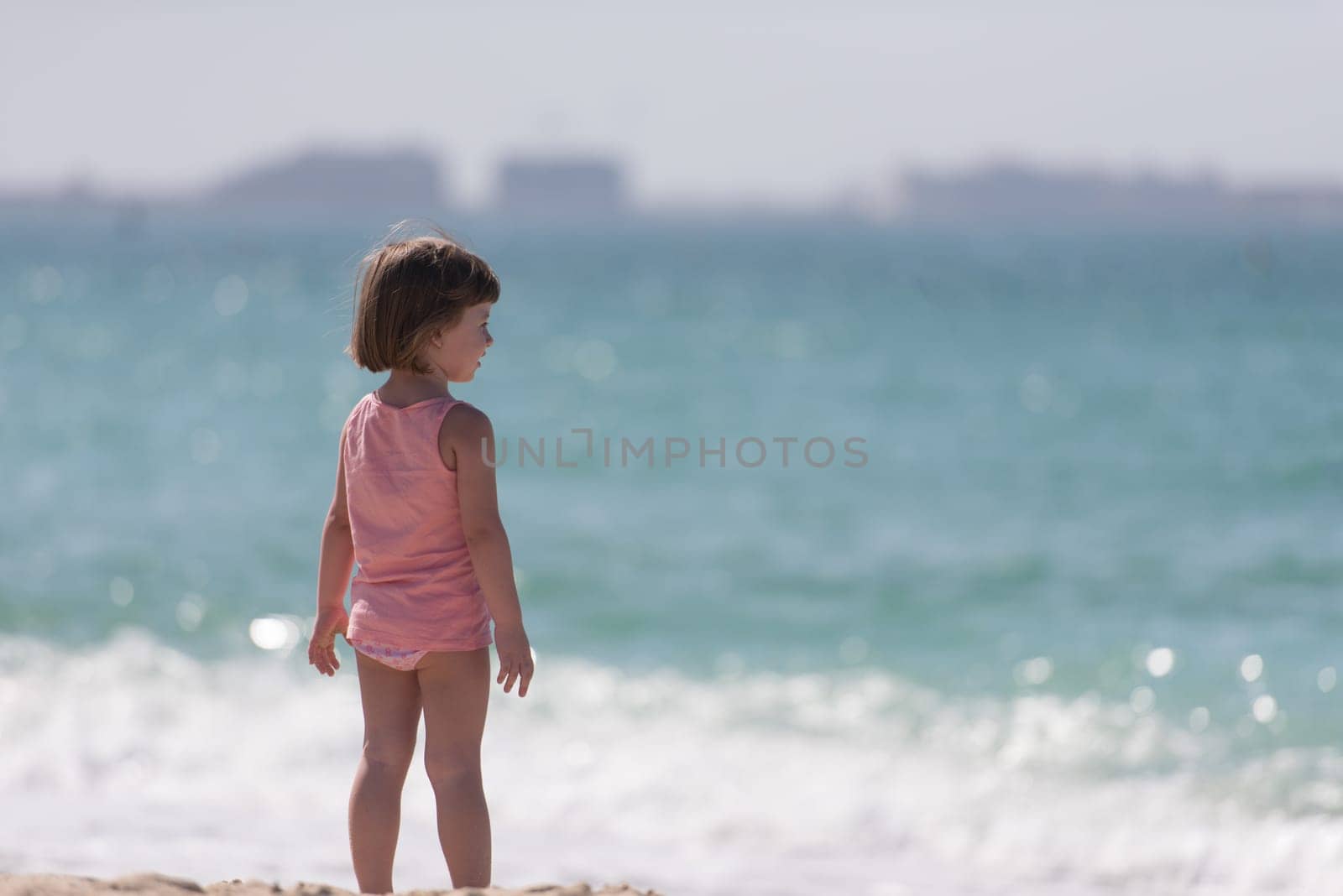 happy little girl at the seaside in the summer.Adorable little girl at beach during summer vacation. Happy baby by the sea or ocean