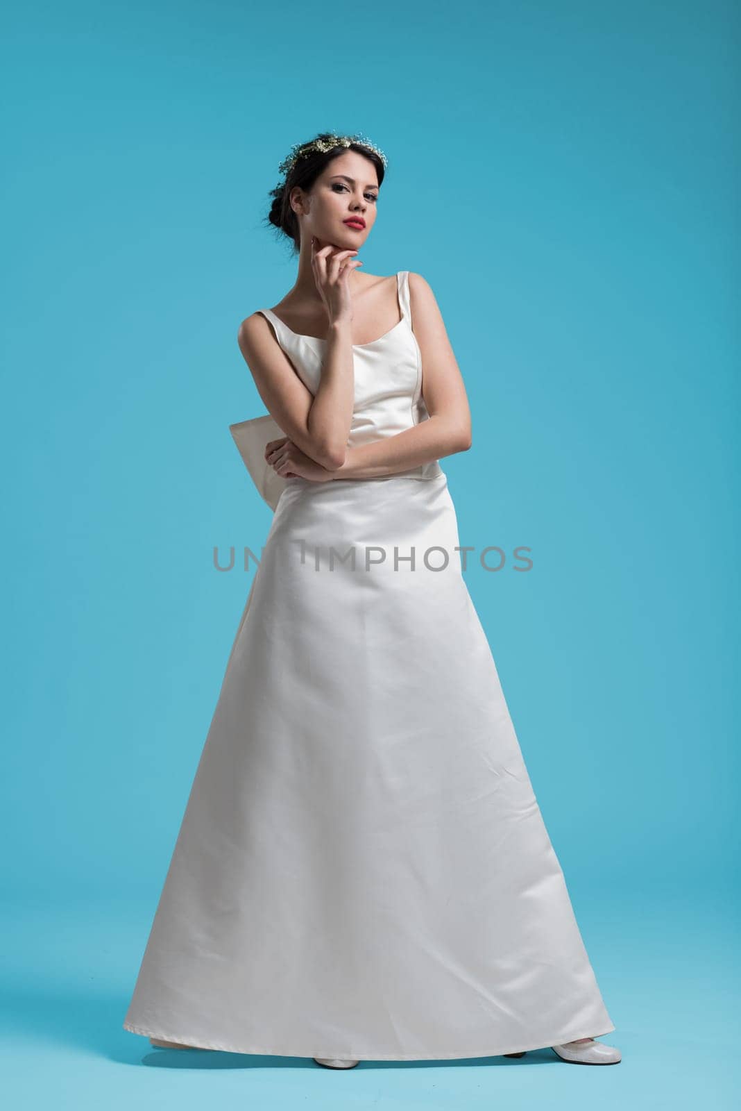 Portrait of beautiful young women in wedding dress isolated on a cyan background