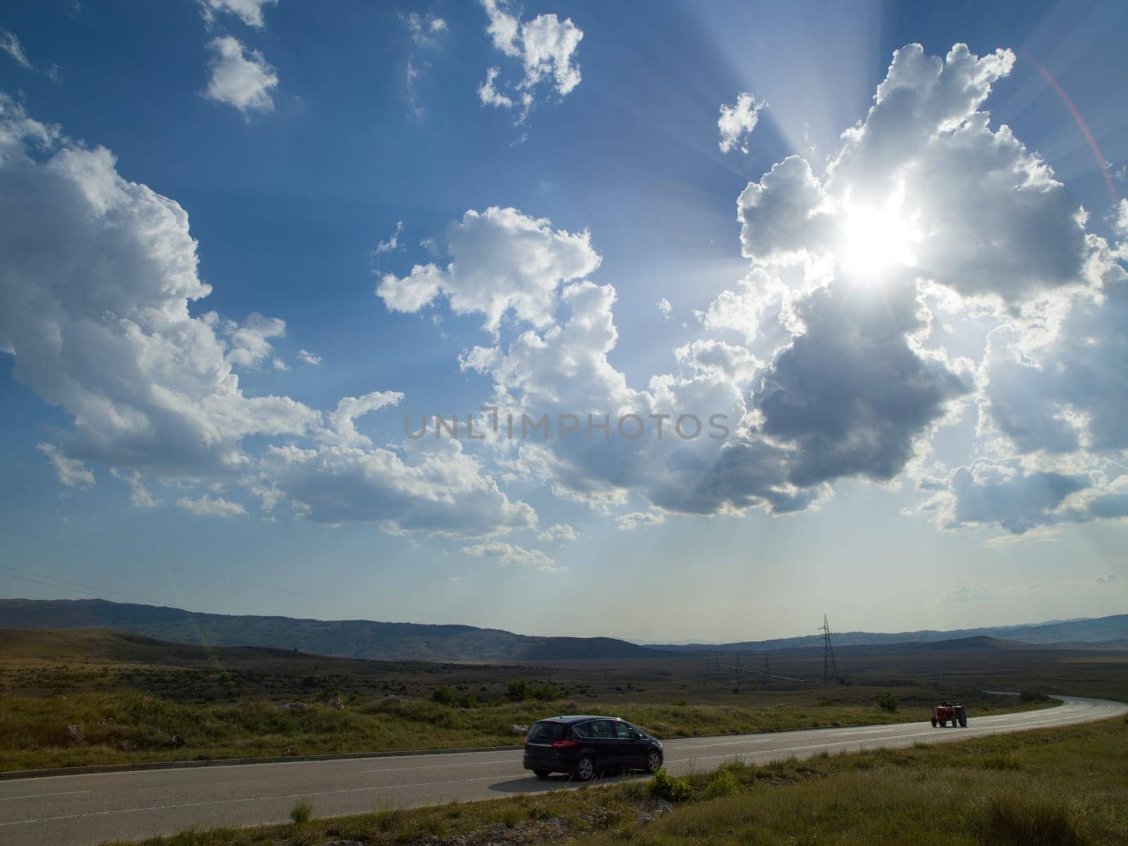 Evening summer landscape with green grass, road and clouds