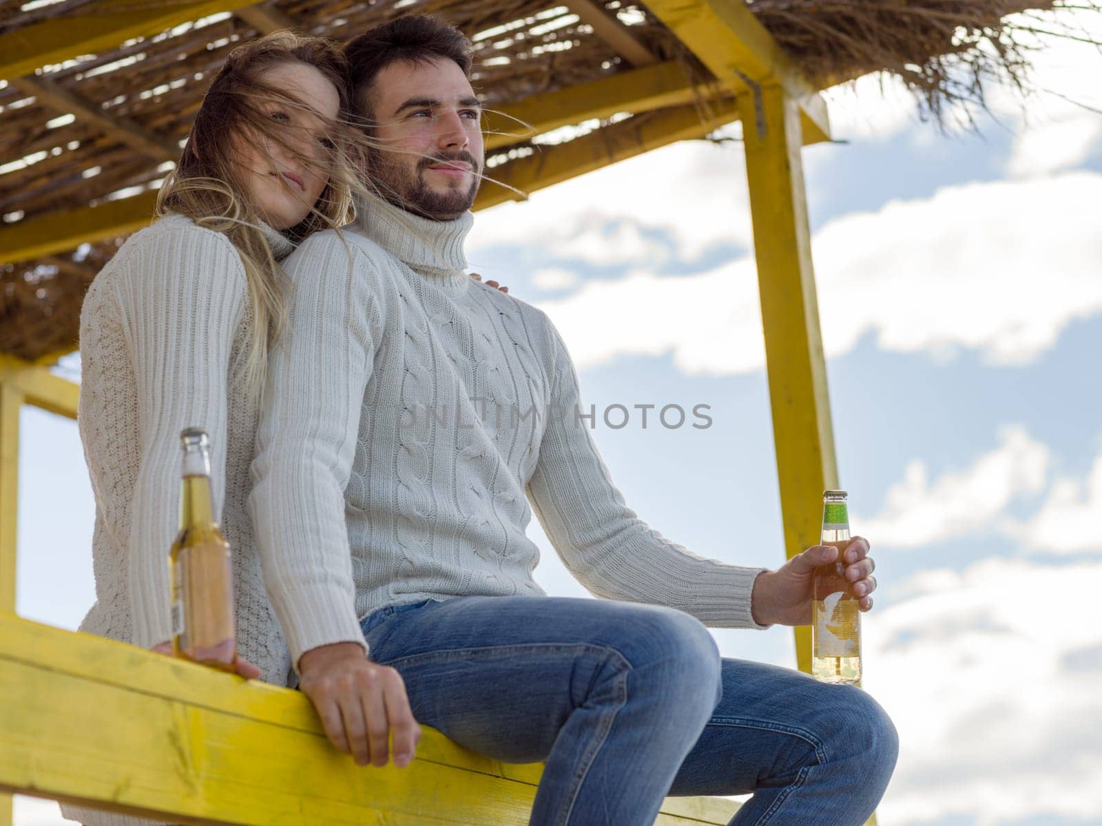 Couple Drinking Beer Together in empty beach bar during autumn time