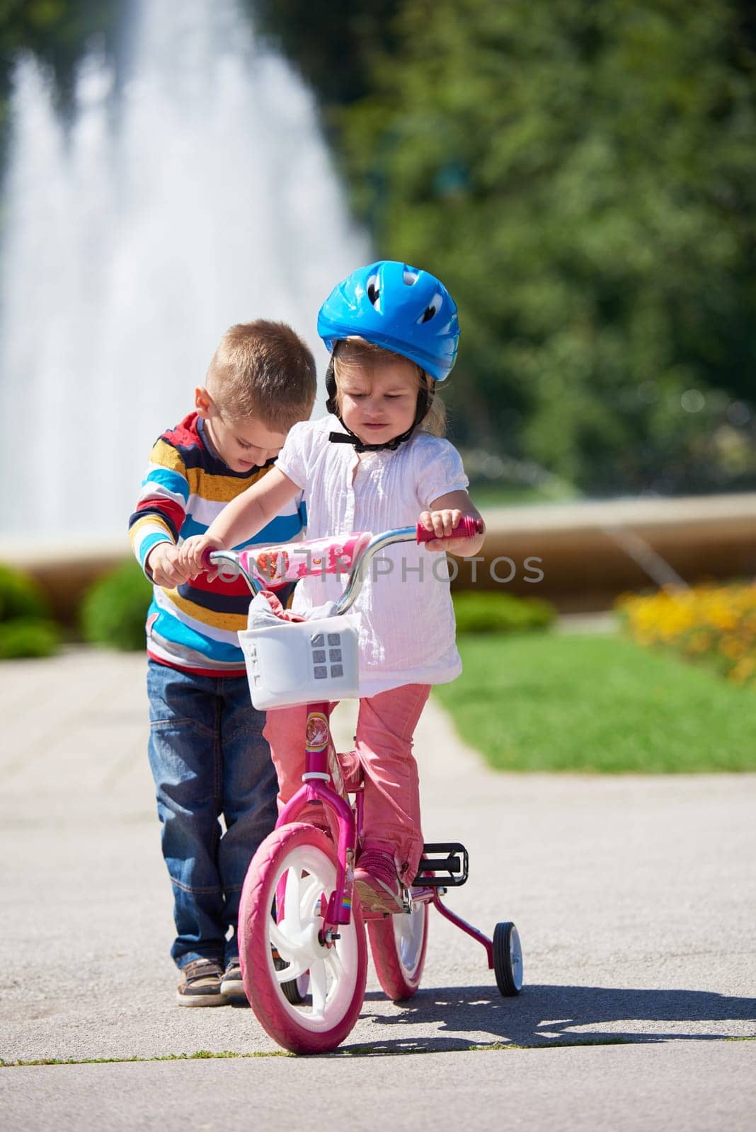 Happy childrens outdoor,  brother and sister in park have fun. Boy and girl in park learning to ride a bike.
