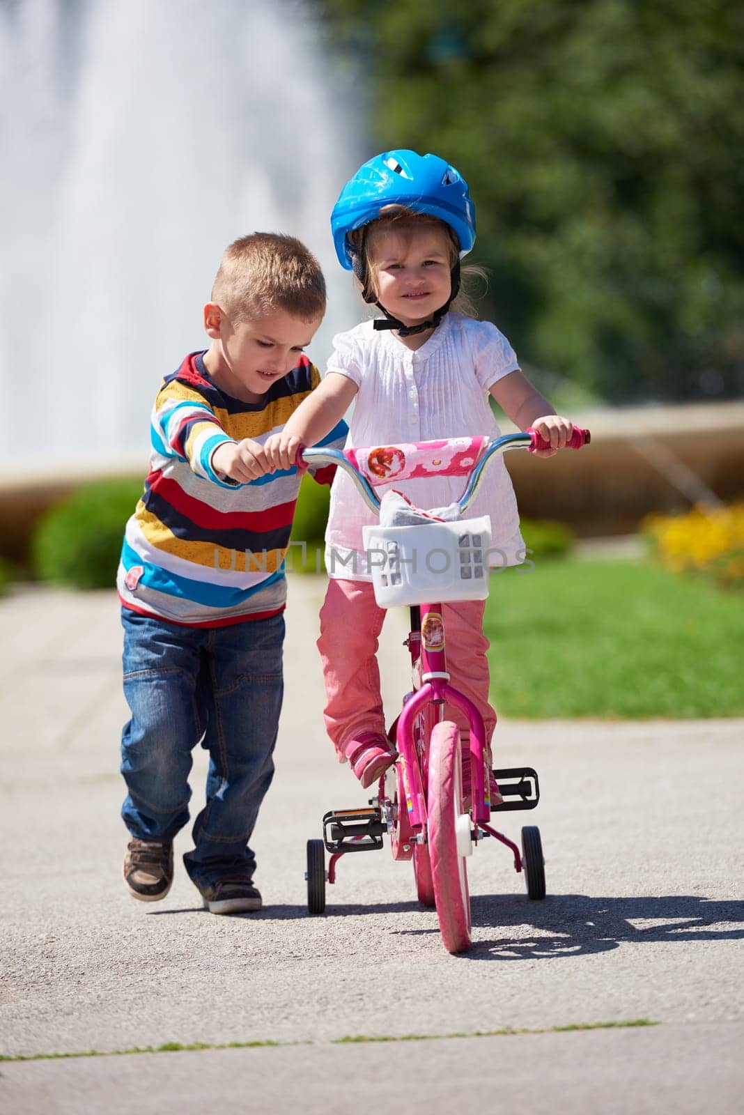 Happy childrens outdoor,  brother and sister in park have fun. Boy and girl in park learning to ride a bike.