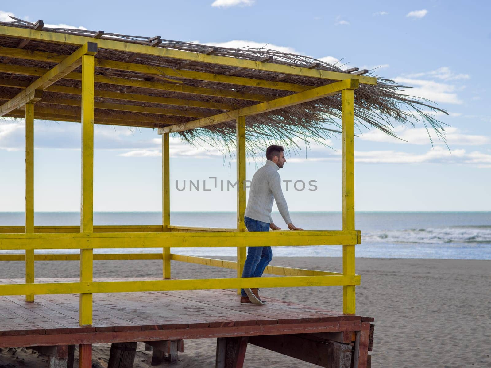Young man on the beach. The guy enjoying the warm autumn day. Portrait of man near the water